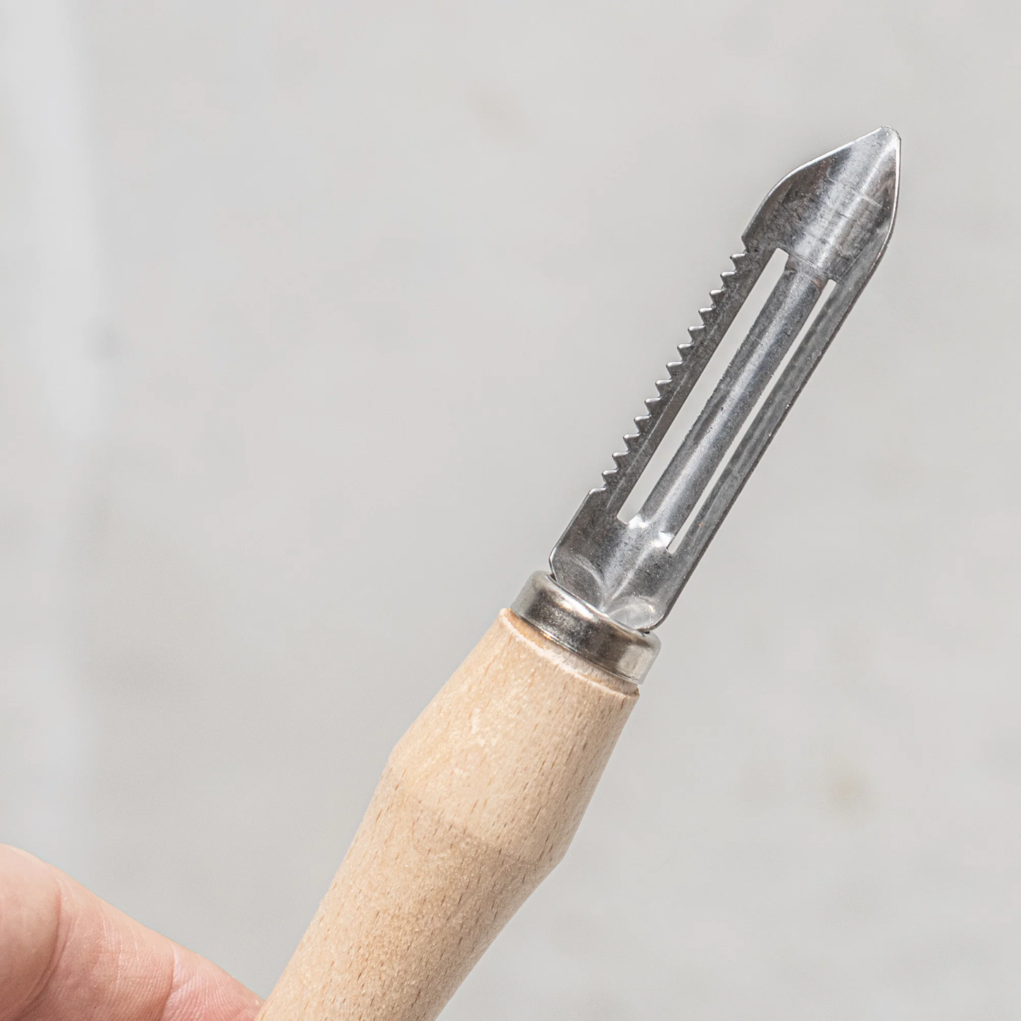 Close up of Fathom Vegetable Peeler Stainless Steel with Beach Handle designed for minimal effort featuring a sharp blade and ergonomic handle for precise control.