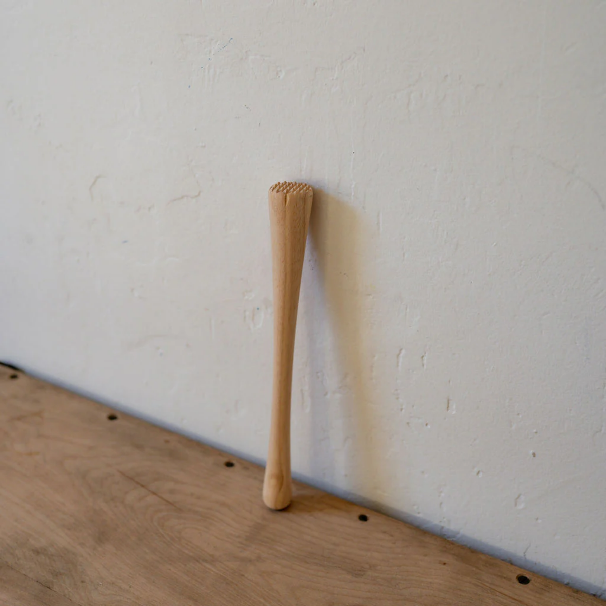Wooden cocktail muddler side view on displayu on wooden table top