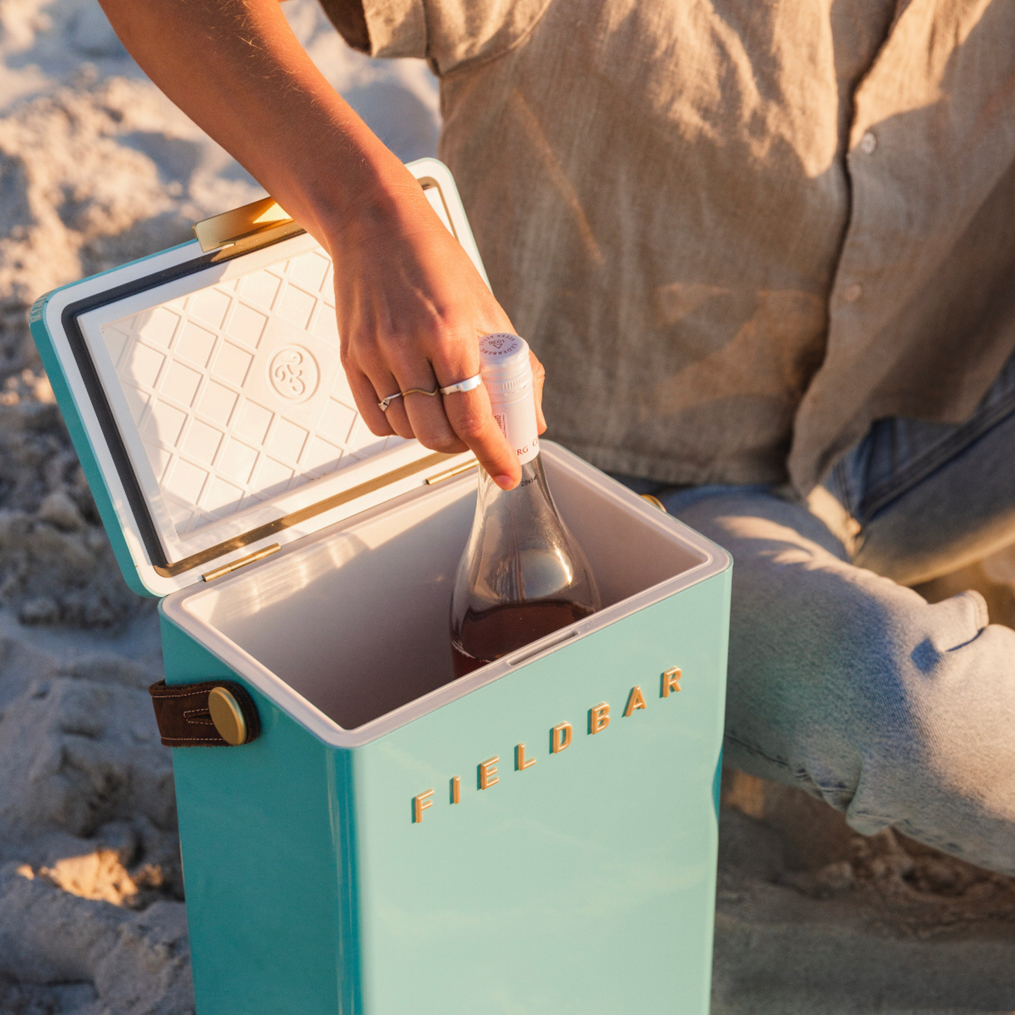 Front view of FIELDBAR Drinks Box MK II hardcase cooler, Bazaruto blue, 10L capacity, durable and comfortable to carry, shown with two wine bottles inside.