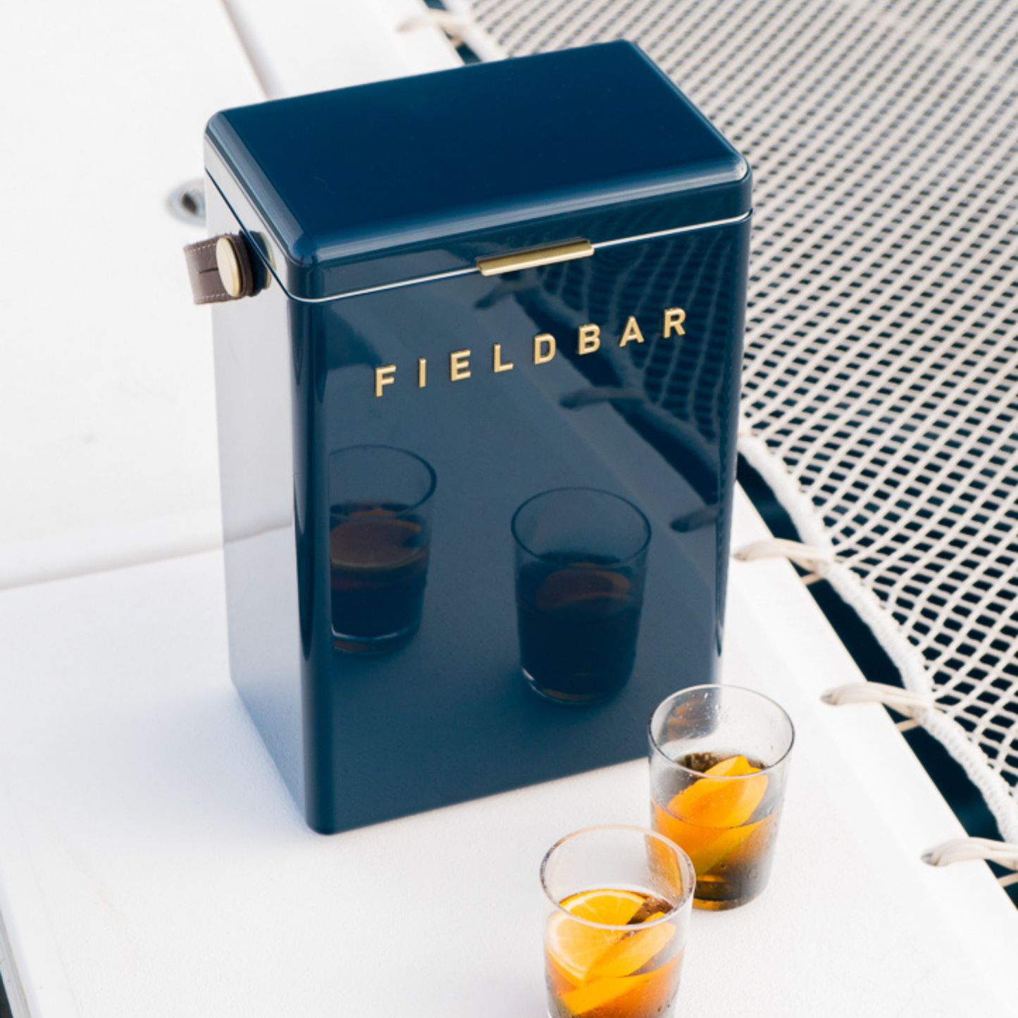 Front view FIELDBAR Drinks Box MK II hardcase cooler, Sea boat blue, 10L capacity, durable and comfortable to carry, shown in a boat with glasses beside it.