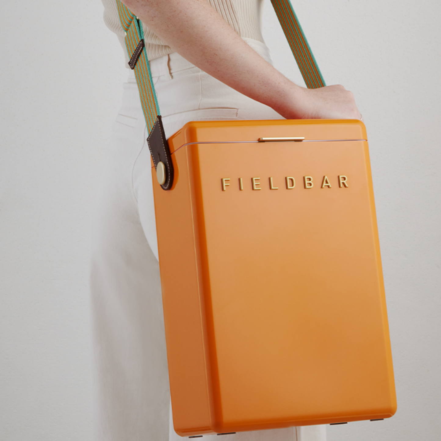 Shoulder carried FIELD BAR Drinks Box Swing Sling, Orange orchard and Parisian green, adjustable from 94.5cm to 147cm, genuine leather, comfortable on shoulder, shown attached with the cooler.