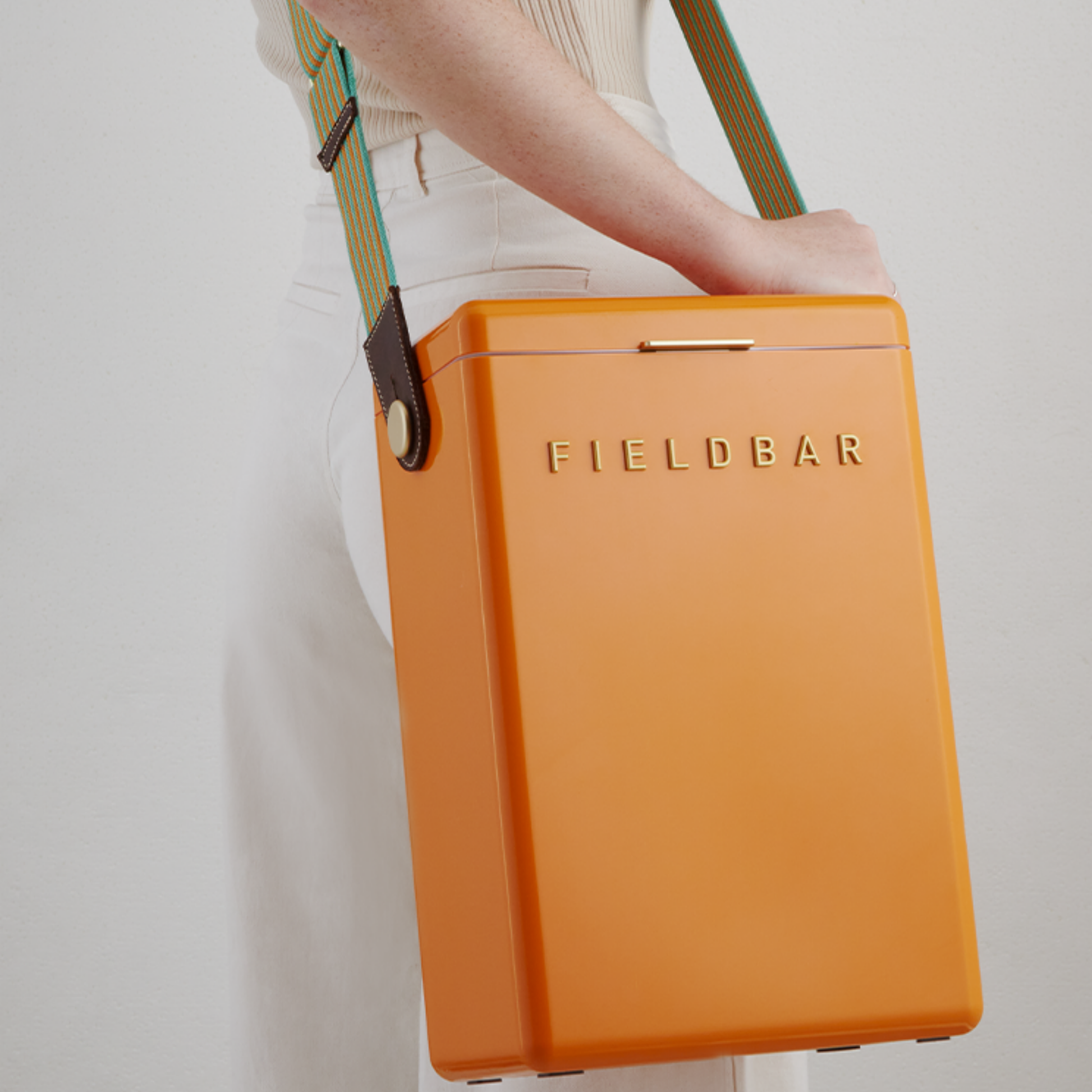 Shoulder carried FIELD BAR Drinks Box Swing Sling, Orange orchard and Parisian green, adjustable from 94.5cm to 147cm, genuine leather, comfortable on shoulder, shown attached with the cooler.