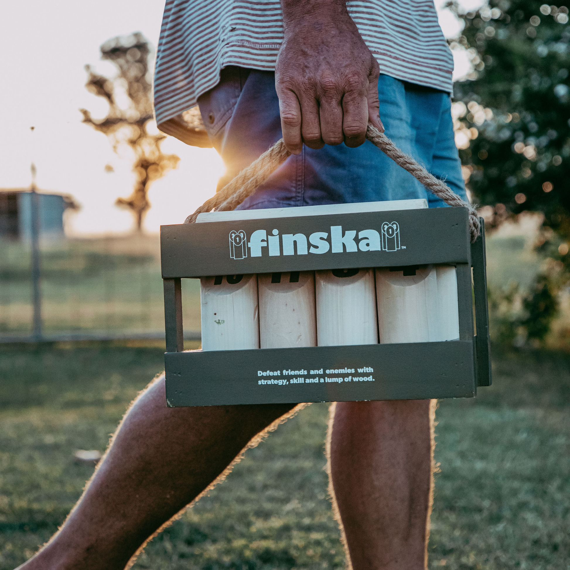 Carried through the handle Finska in Moss Green outdoor throwing game set made from eco-friendly birch hardwood, includes 12 numbered pins, a throwing log, and a green painted carry crate.