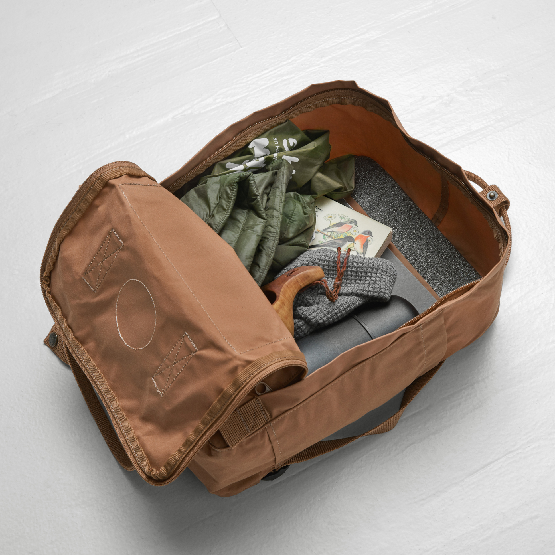 Open with things like cloth and tumbler inside, The Fjallraven Kanken Backpack which is made from hard-wearing Vinylon F fabric and features a spacious main compartment with a full-length zip, removable PE foam seat cushion, two flat side pockets, a zipped front pocket, adjustable shoulder straps, and top handles. Durable and practical backpack for everyday use.
