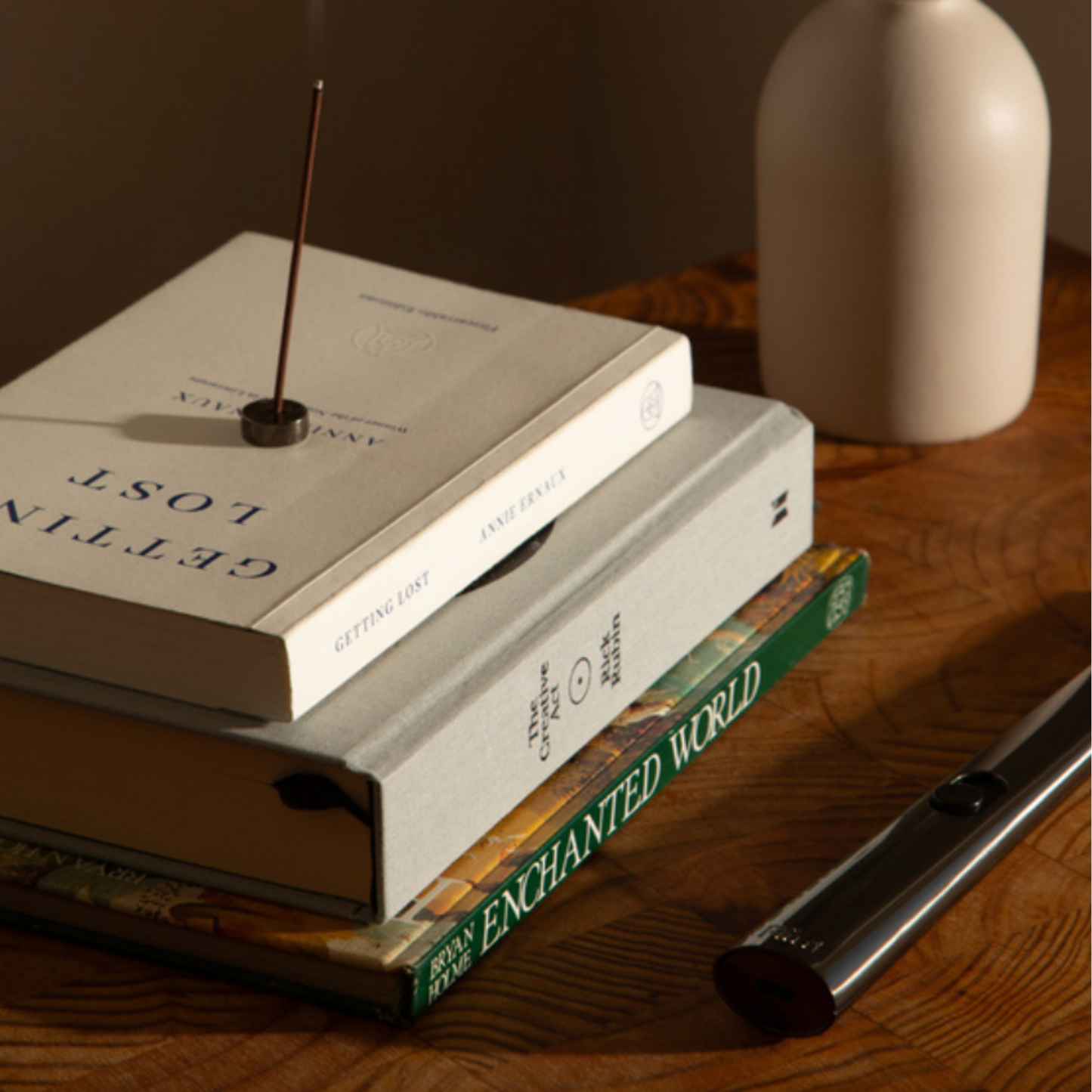 Flint rechargeable gunmetal lighter on wooden coffee table next to books and incense 