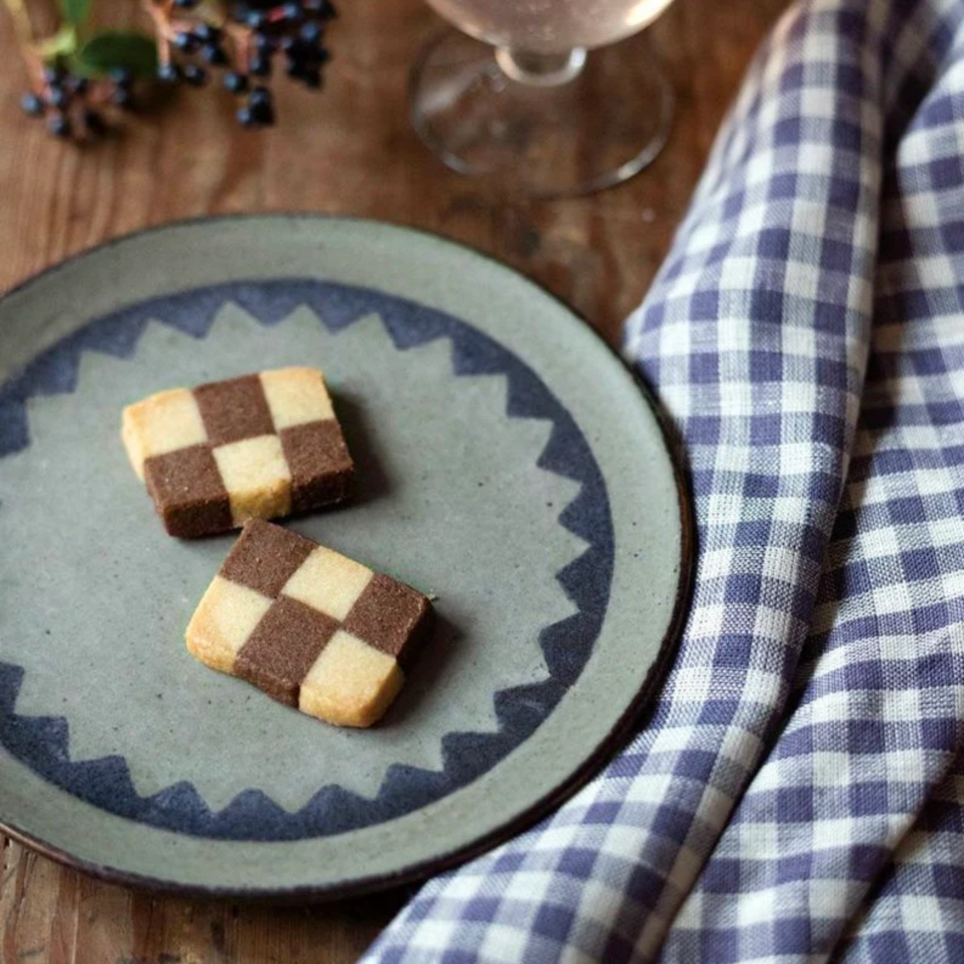 Fog Linen cloth tea towel simone on wooden table next to plate of biscuits.