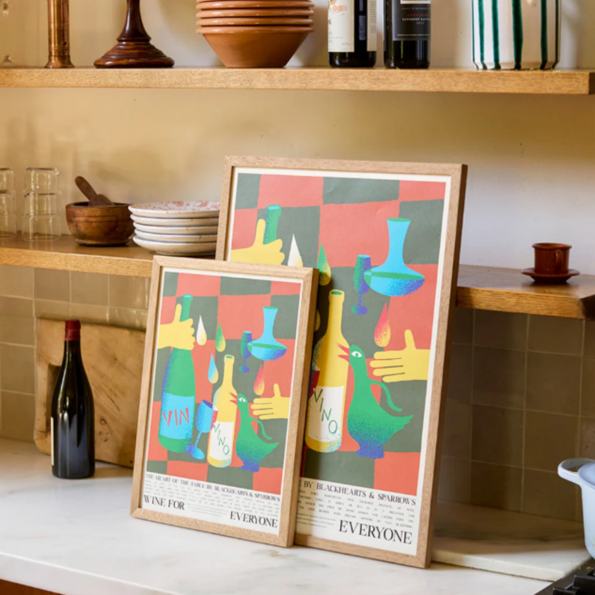 Two frames on the table Food for Everyone Wine Poster created with Blackhearts & Sparrows and artist Max Blackmore, featuring warm wine tones that celebrate shared meals and laughter; printed on recycled paper, unframed
