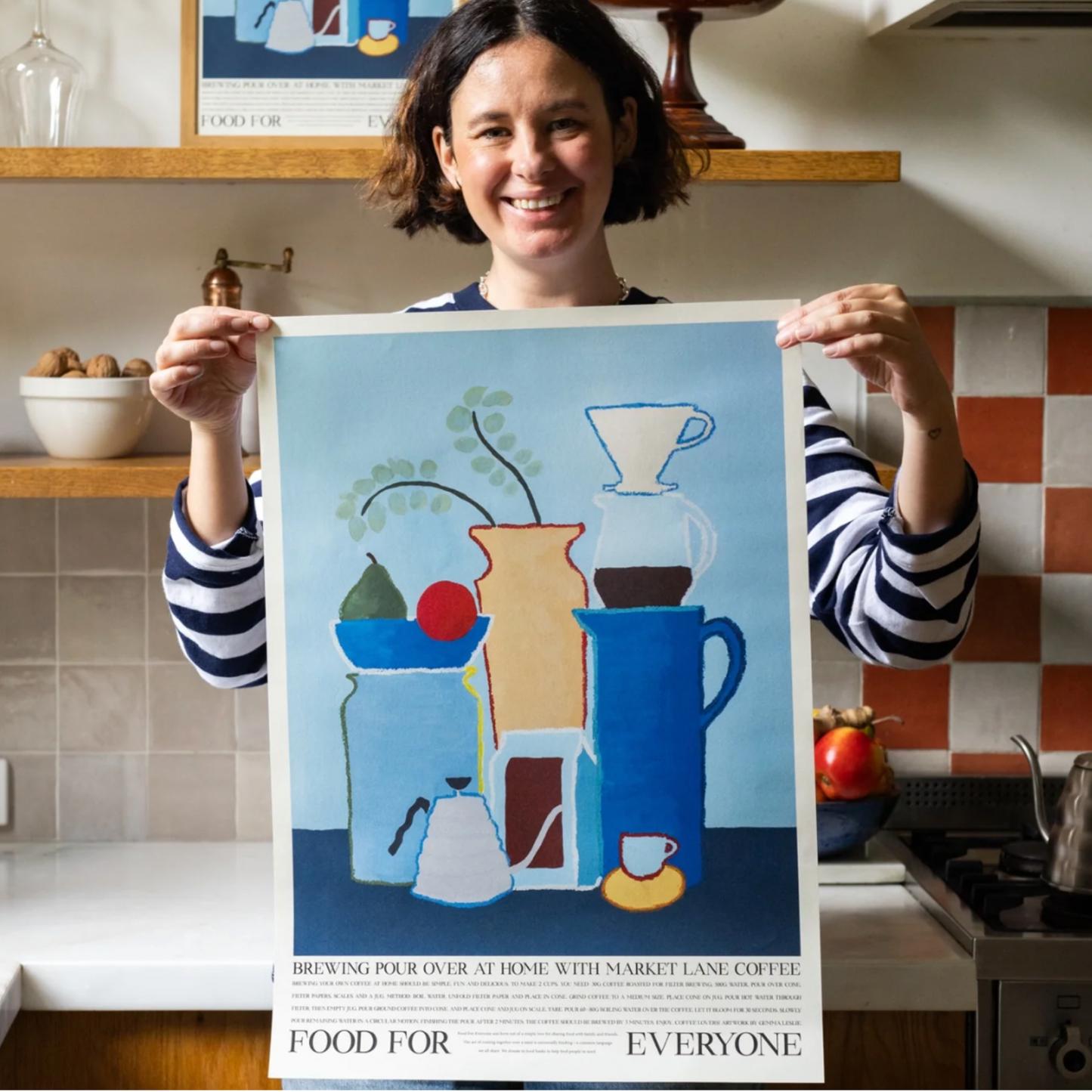 Woman holding Food For Everyone Pour Over at Home artwork A2 front out of frame in kitchen
