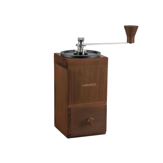 Semi side view of the Hario Coffee Mill Cube 3-4 cups wooden coffee grinder with ceramic burr and stainless steel handle.