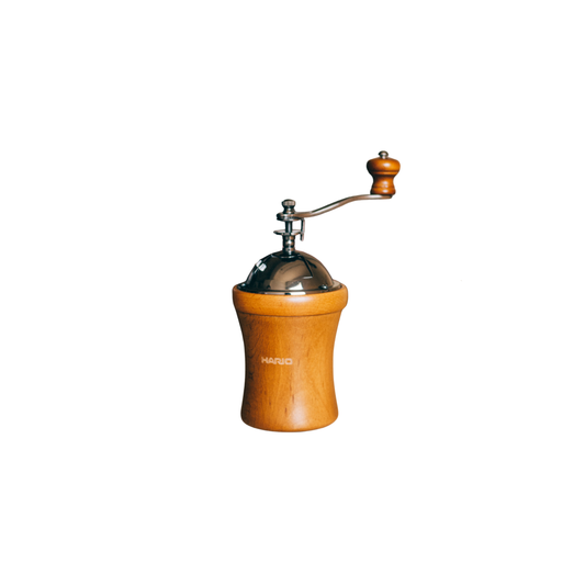 Hario Dome Coffee Mill, natural wood finish with rounded body and tapered center for easy grip, featuring a hand crank with wood handle and ceramic burr for consistent manual grinding. Compact and rustic design, ideal for 35g of coffee grounds.