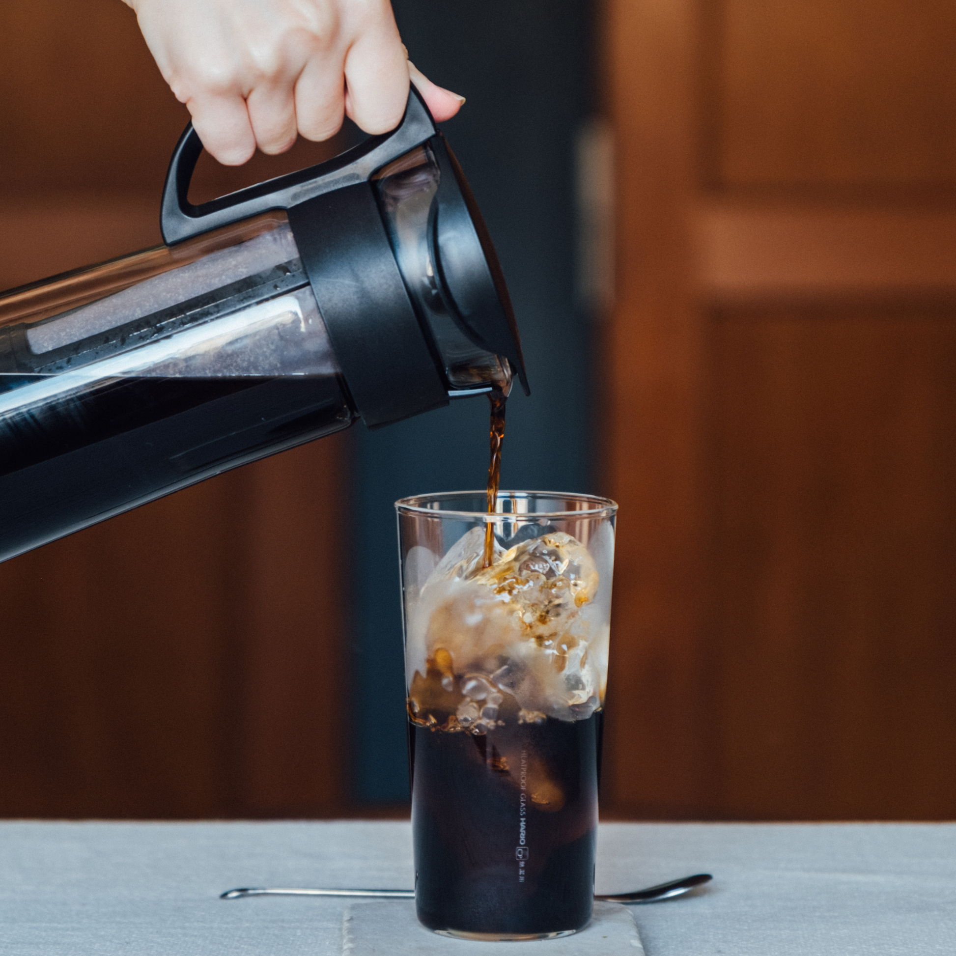 Pouring coffee from Hario Cold Brew Coffee Pot Glass Black that is made from durable heatproof Hario glass, foolproof design with 1L capacity.