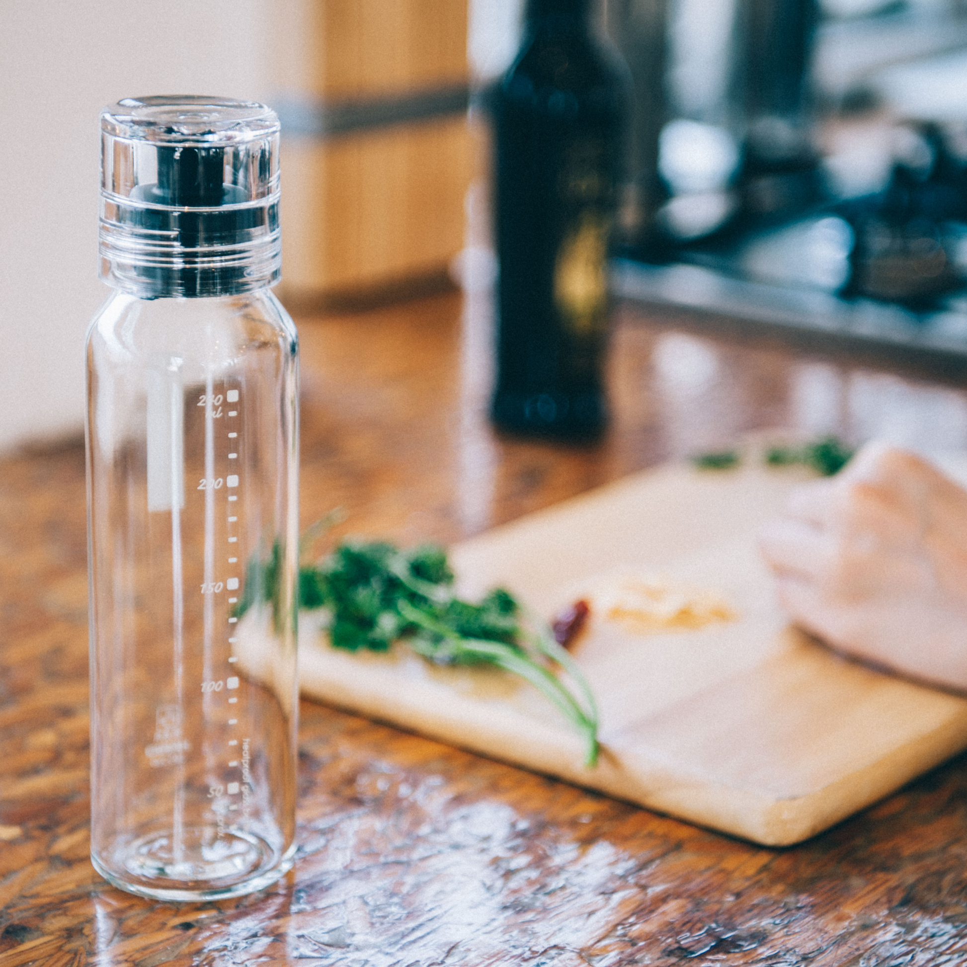 In table setting of HARIO Dressing Bottle, 250mL capacity, heatproof glass with twist cap and modest pouring spout, available in Pale Grey and Black. Designed for shaking, pouring, and storing homemade dressings; dishwasher and heat sterilization safe.