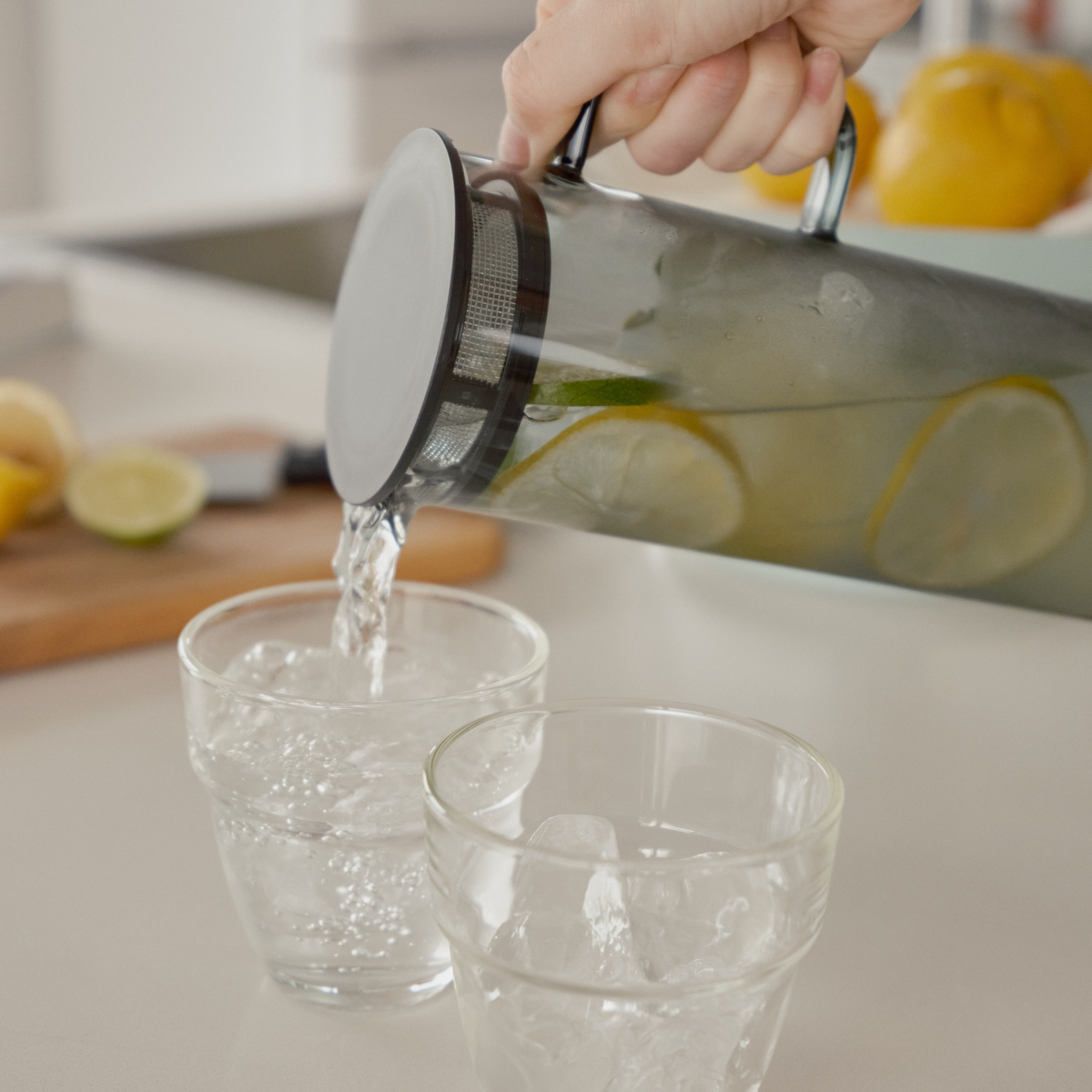 Pouring lemon juice from Hario Glass Pitcher Grey that is made from heatproof glass with 800ml capacity, with a lid that has a mesh filter.