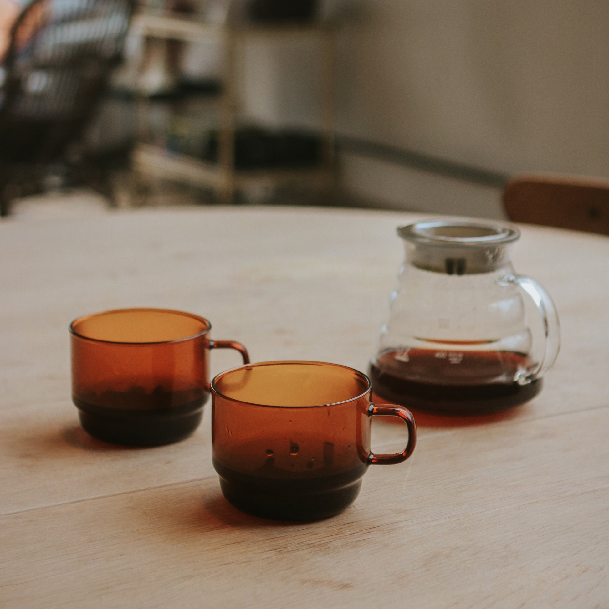 Two Hario Glass Stacking Mug Amber with a glass server on the table that is made from heatproof glass, for 300ml capacity.