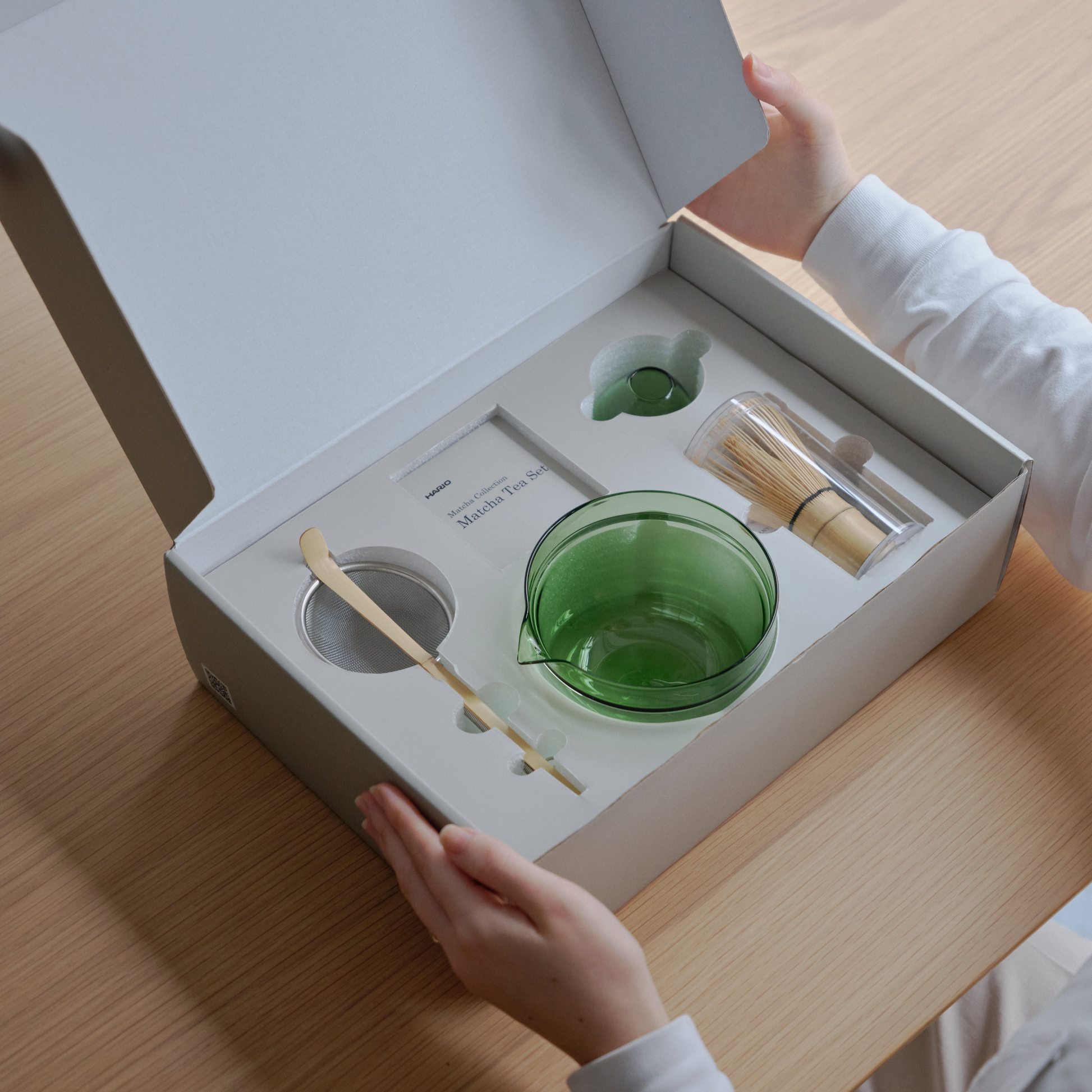 Shown in its box, the Hario Matcha Tea Set Green which includes a double-walled Matcha Bowl, stand from heatproof glass, Chasen or the whisk, chashaku or measuring spoon from bamboo and tea sifter from stainless steel.