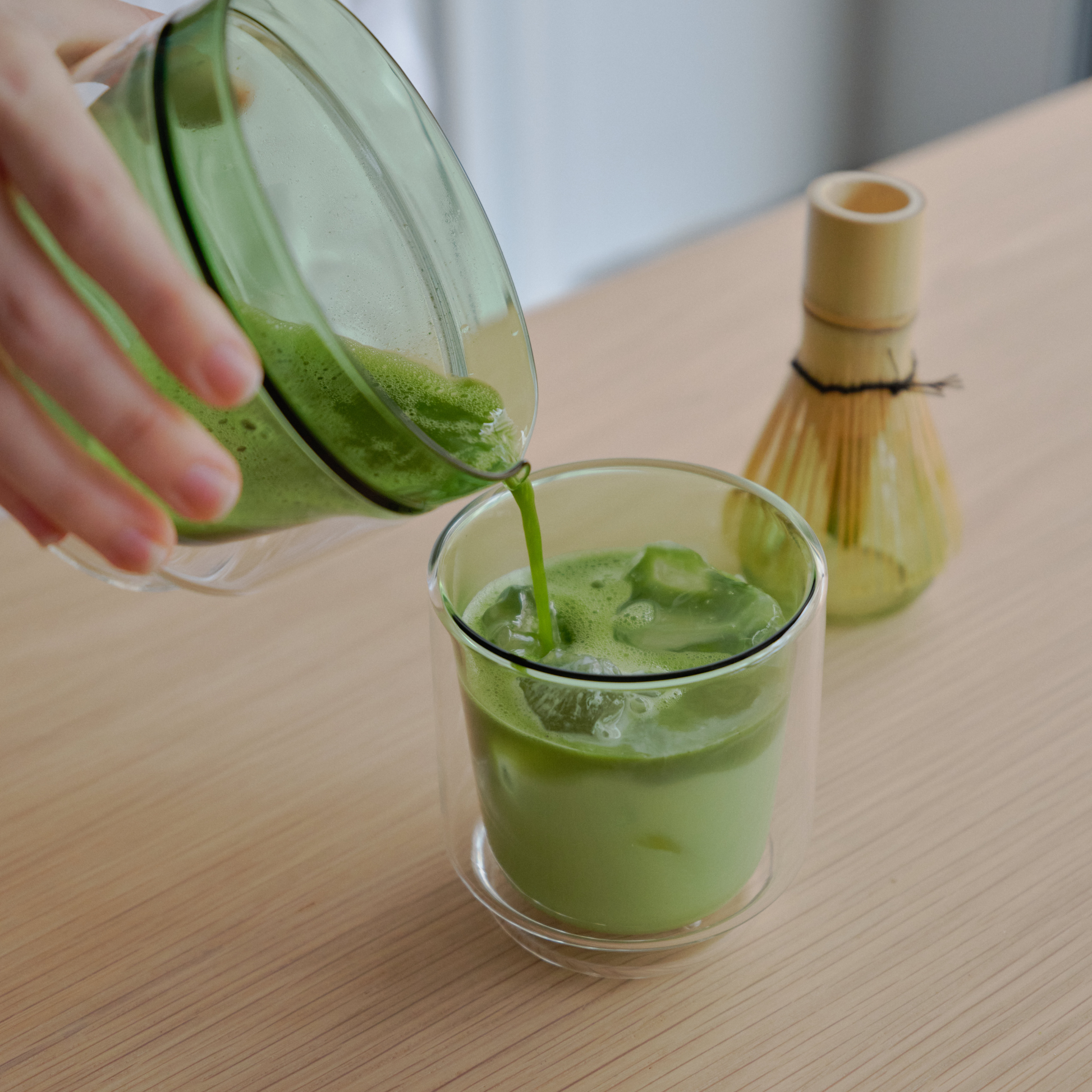 Pouring matcha from the bowl of the Hario Matcha Tea Set Green which includes the double-walled Matcha Bowl, stand from heatproof glass, Chasen or the whisk, chashaku or measuring spoon from bamboo and tea sifter from stainless steel.