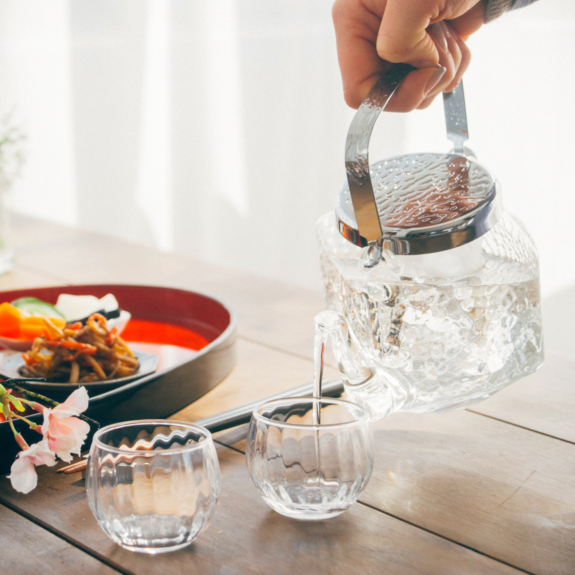 Pouring liquid HARIO Chirori Sake Pot Set, heatproof glass body with stainless steel lid and brass knob, includes glass ice holder to chill without dilution, 360mL capacity, made in Japan.