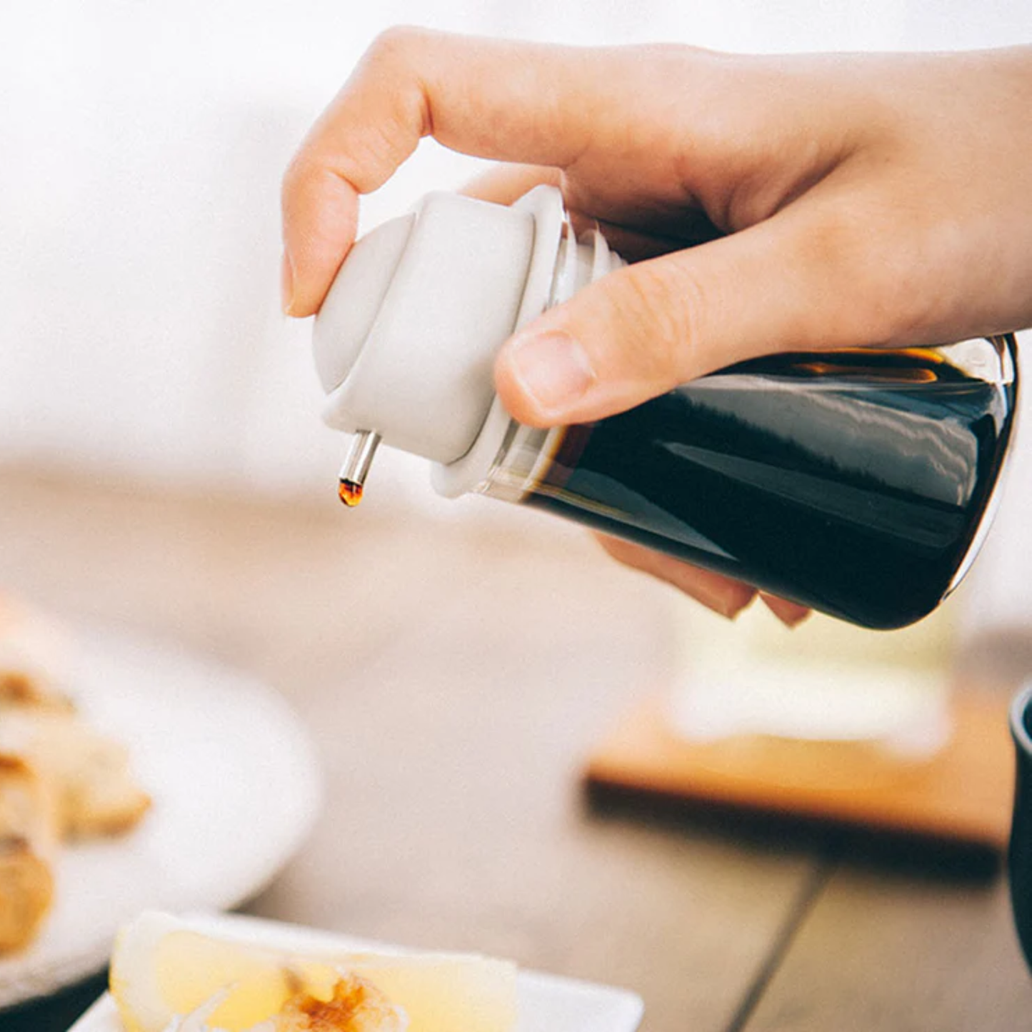 Shown pouring through the One Push Pale grey HARIO Soy Sauce Bottle, refillable 80mL heatproof glass dispenser with stainless steel spout and silicone-sealed lid for easy, spill-free pouring.
