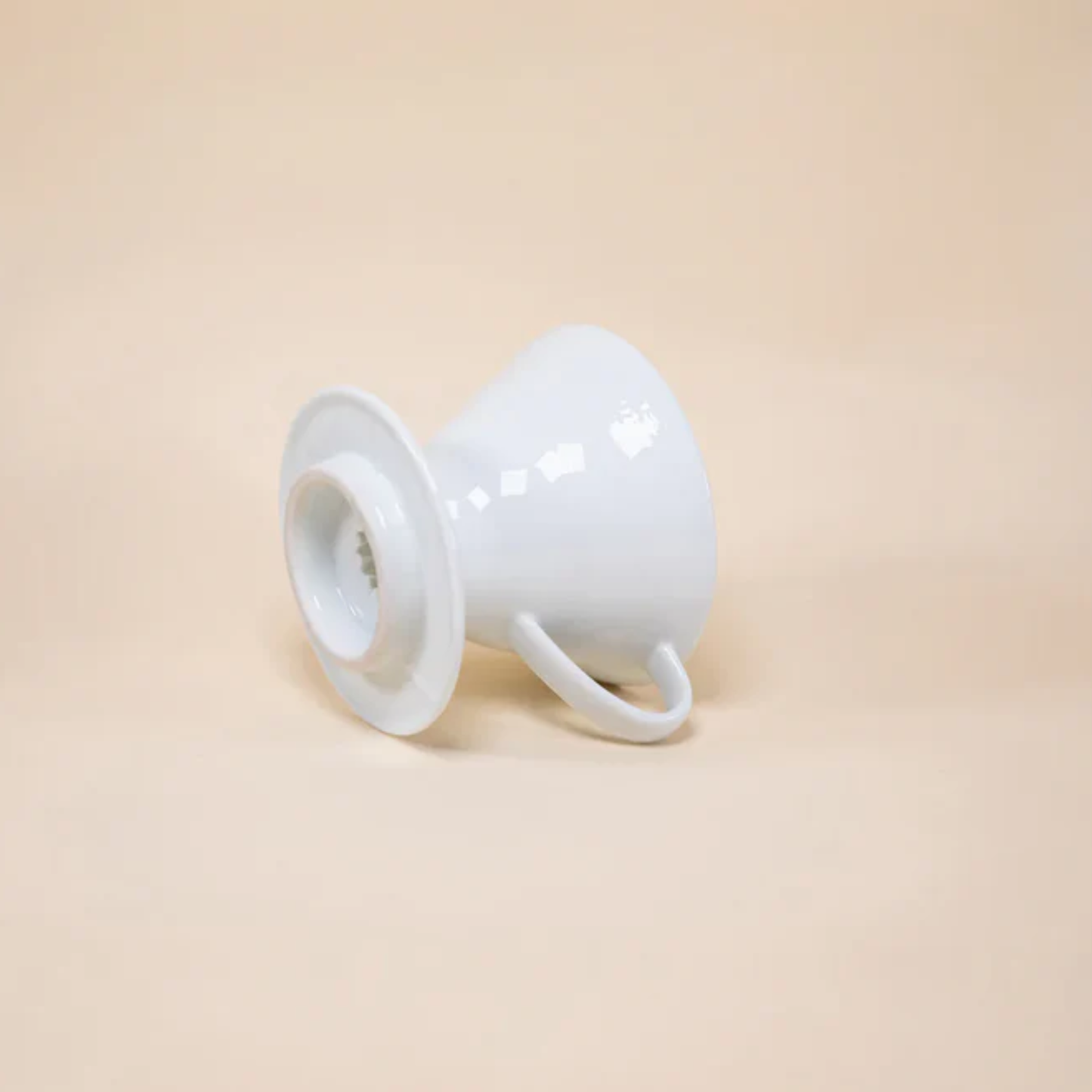 Laid and showing the bottom part of HARIO V60 ceramic coffee dripper white porcelain with spiral ridges and conical shape for adjustable brewing flow, includes polypropylene measuring spoon.