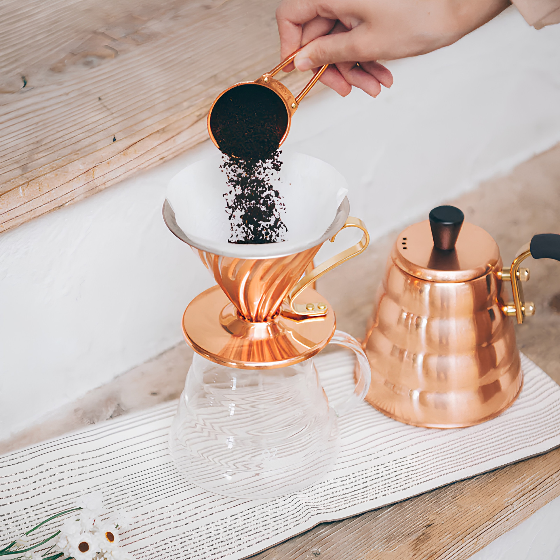 Coffee powder being put inside the Hario V60 Copper Coffee Dripper 02 Copper that has the capacity of 1-4 cups, and weighs approximately 300g, featuring heat distribution evenly and antibacterial property of copper, widely used for kitchenware.