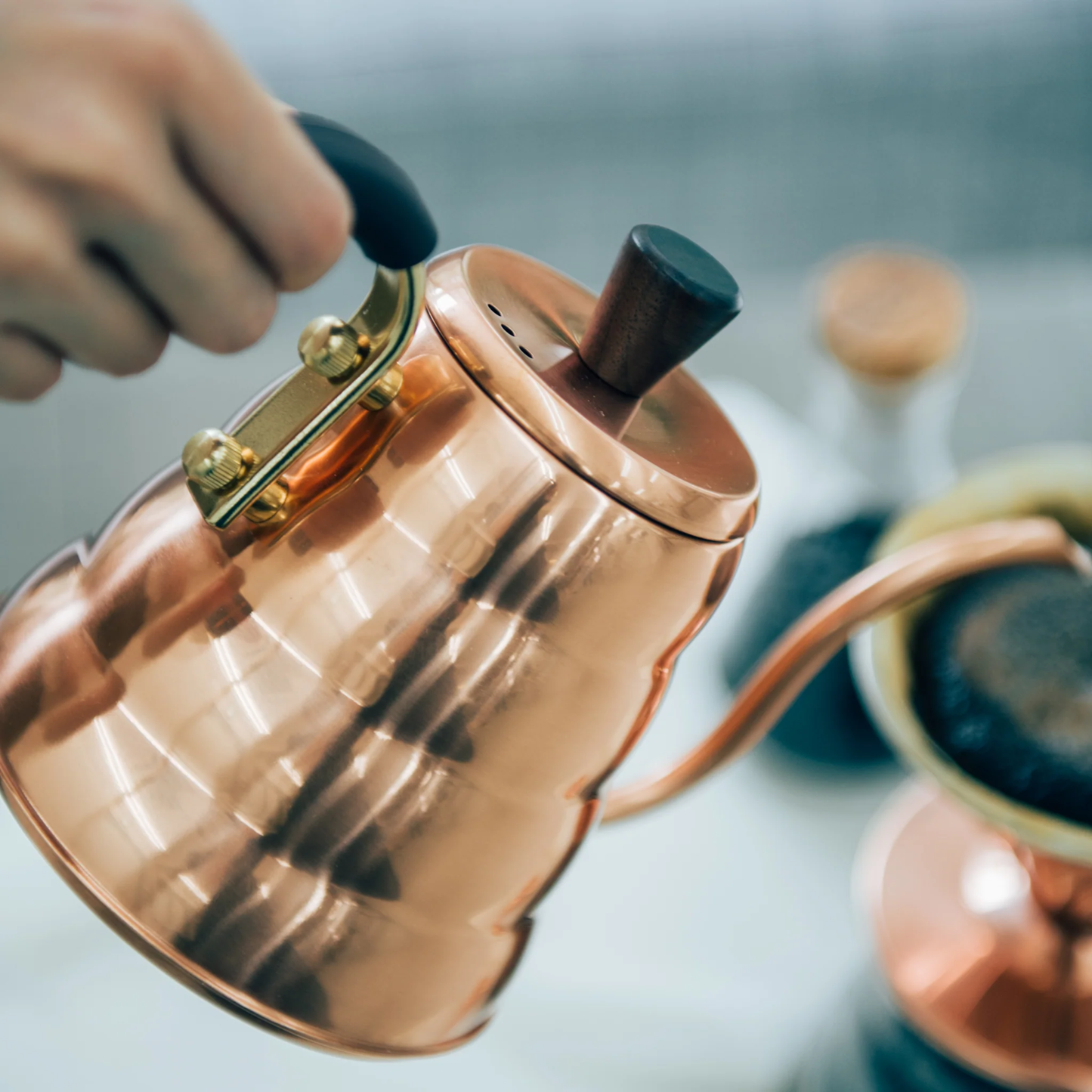 Close up on the Hario V60 Drip Kettle Buono 700ml Copper which includes Body of kettle and lid from copper, nickel and sealed with baked coating, lid knob from natural wood, handle from brass and handle cover from silicone rubber, luxurious of all kettles, iconic shape.