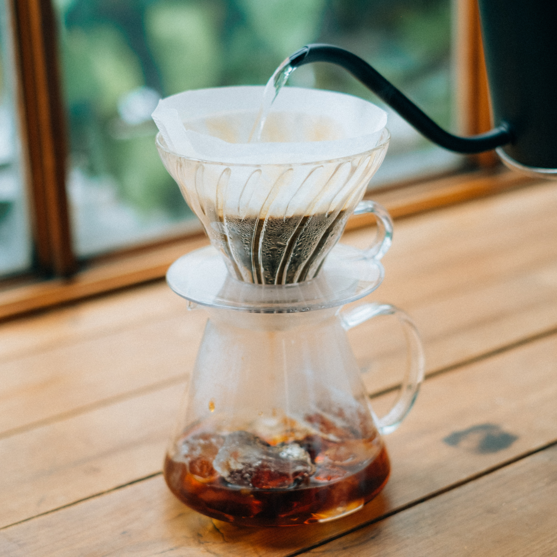 Pouring hot water on the powdered coffee in the HARIO V60 glass dripper set clear heatproof glass with dripper, server, filter paper, and polypropylene measuring spoon for 1 to 4 cups.