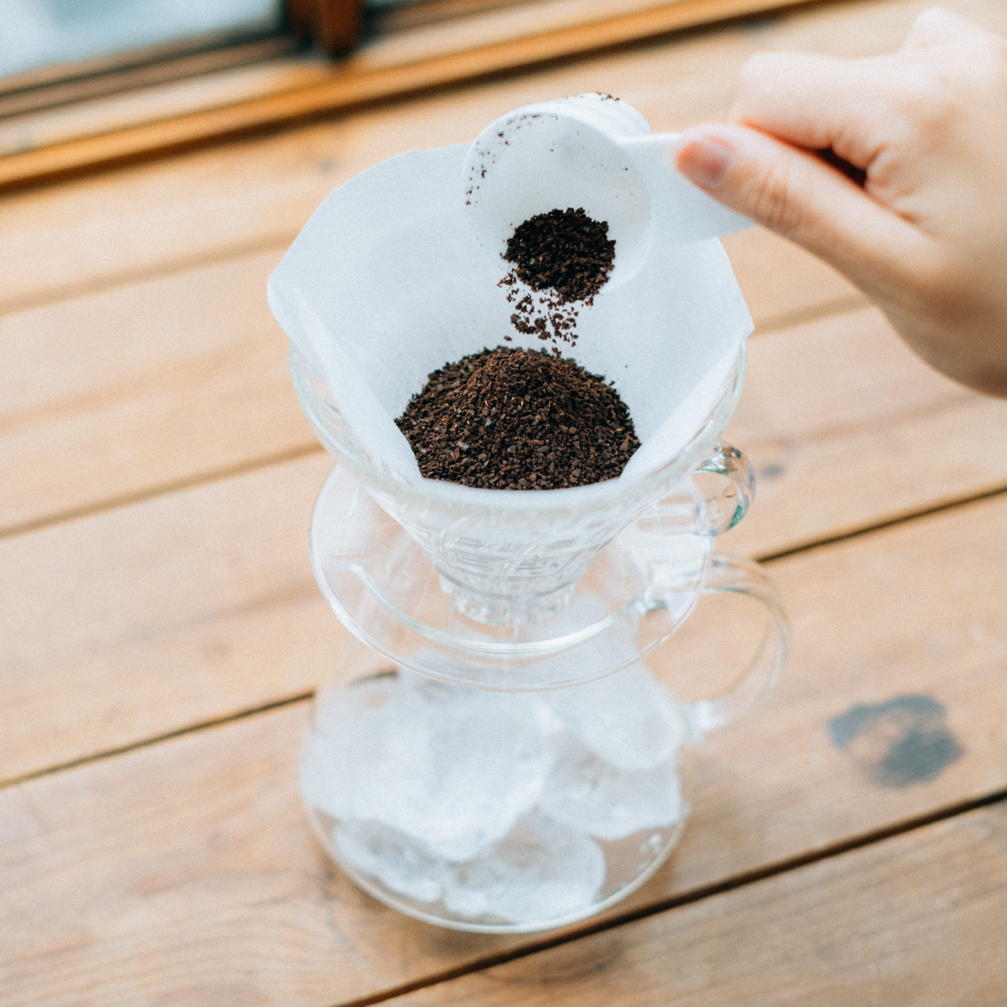Putting coffee powder in the HARIO V60 glass dripper set clear heatproof glass with dripper, server, filter paper, and polypropylene measuring spoon for 1 to 4 cups.