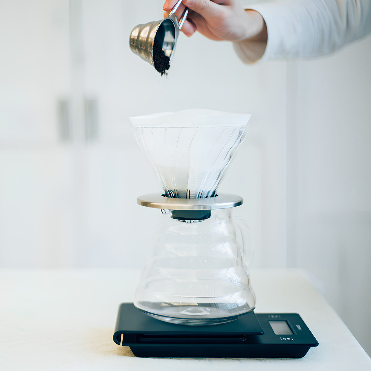 Putting ground coffee to the coffee dripper using the Hario V60 Measuring Spoon made from stainless steel designed to complement the v60 series, perfect gift for the barista, with 12g ground coffee capacity, made in Japan.