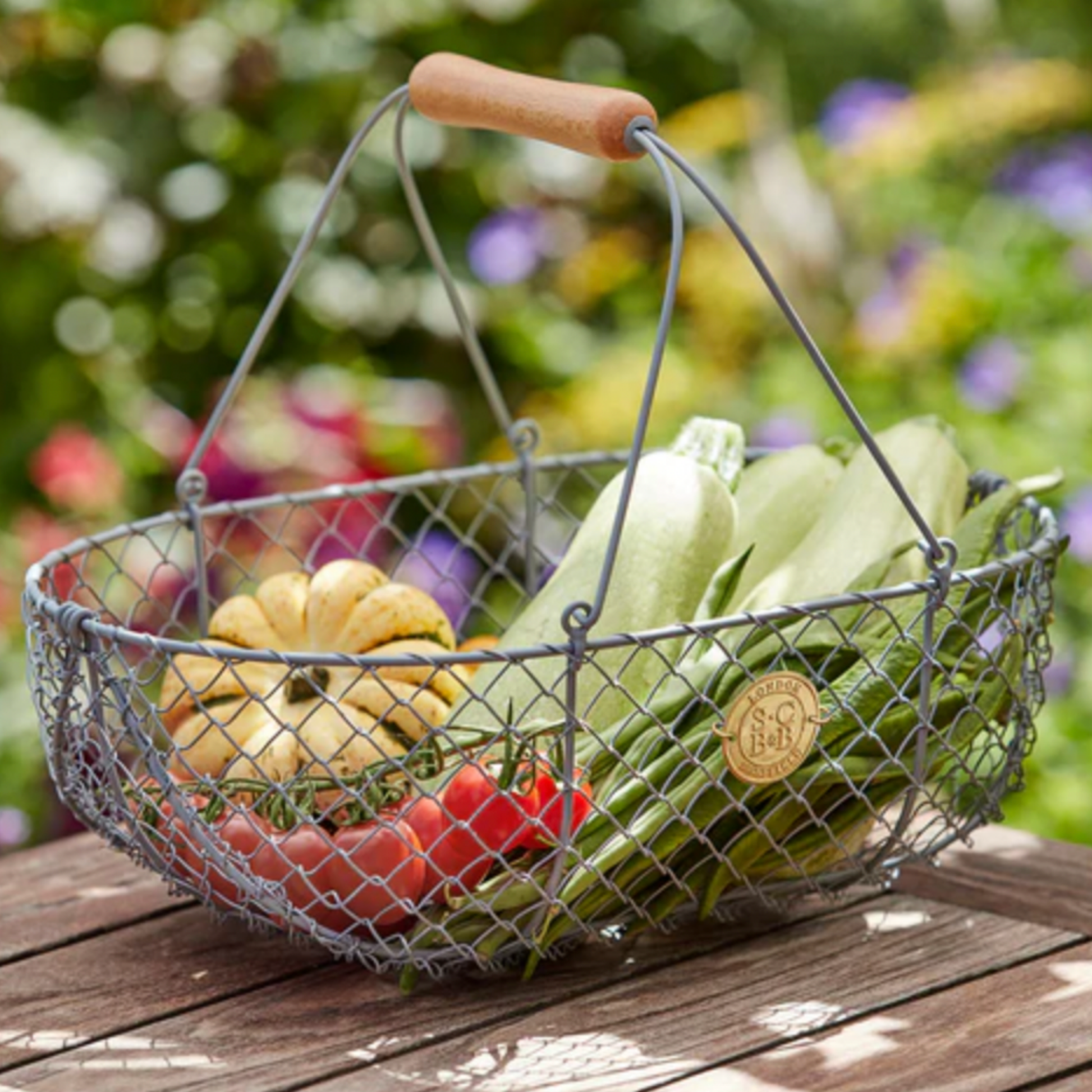Burgon & Ball wire grey harvesting basket on wooden table with vegetables in basket