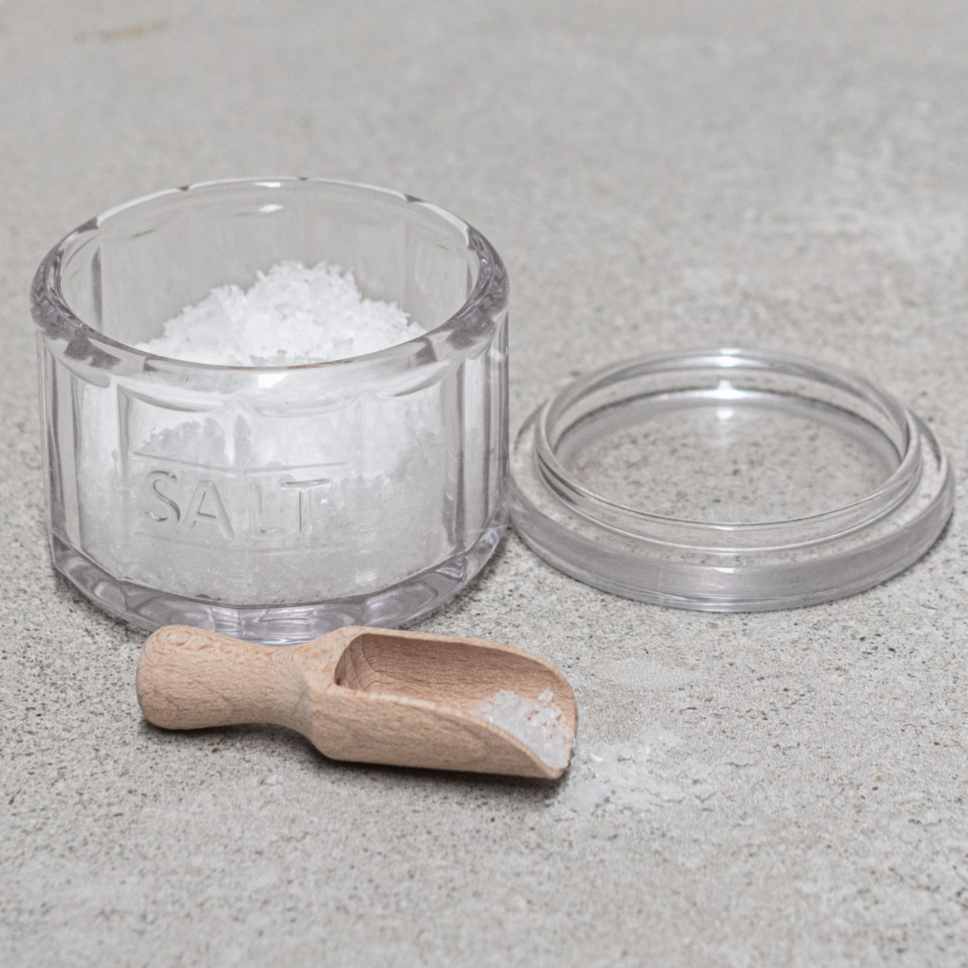 Heaven in Earth Glass Salt Pot & Wooden Scoop with salt in pot on concrete table 