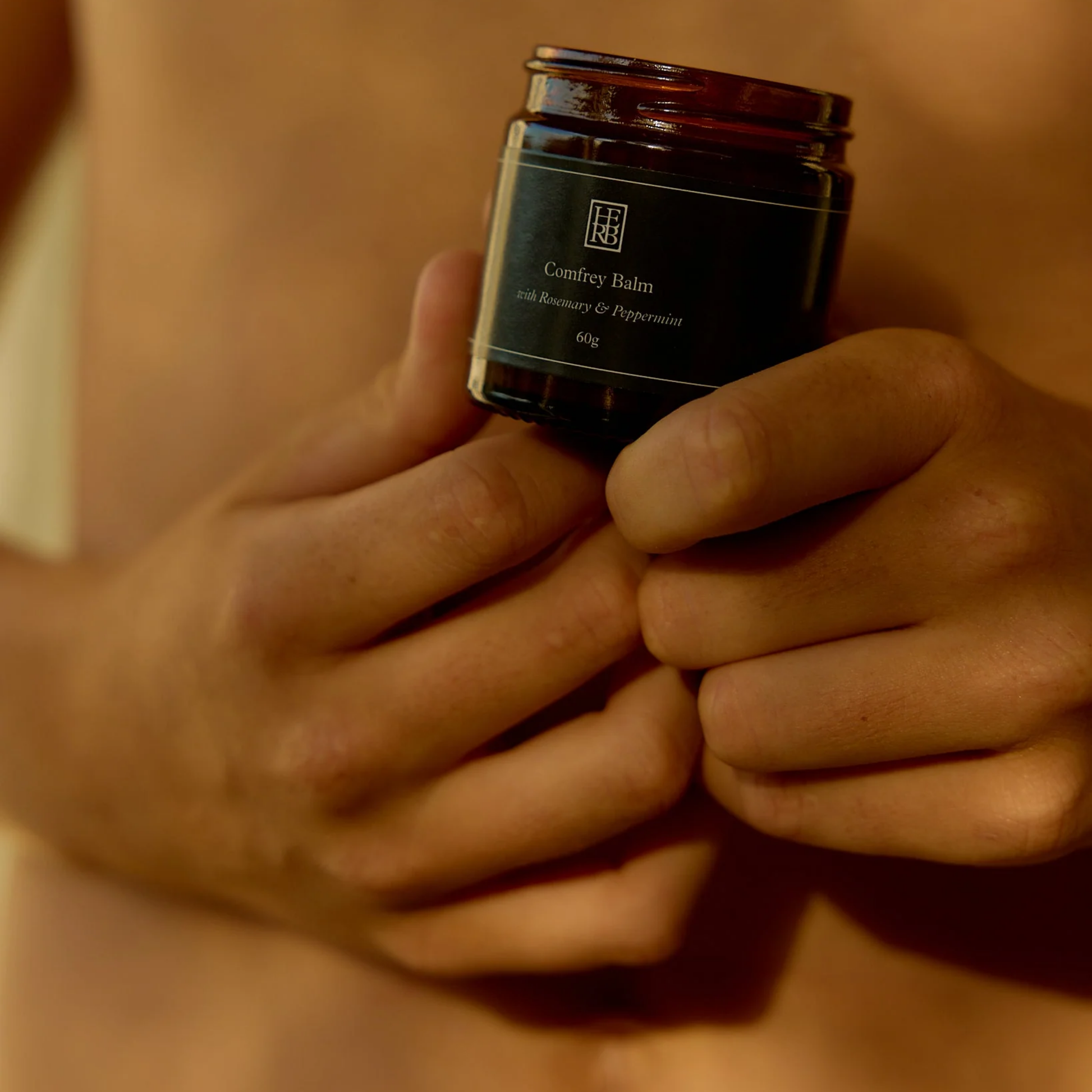 Shown being held Herb Remedy Comfrey Balm - Deep tissue healing and skin regeneration balm made from comfrey-infused olive oil - Enriched with peppermint and rosemary essential oils for soothing, cooling, and anti-inflammatory relief - Ideal for bruises, sprains, strains, and muscle soreness - Natural herbal balm promoting tissue repair and faster recovery