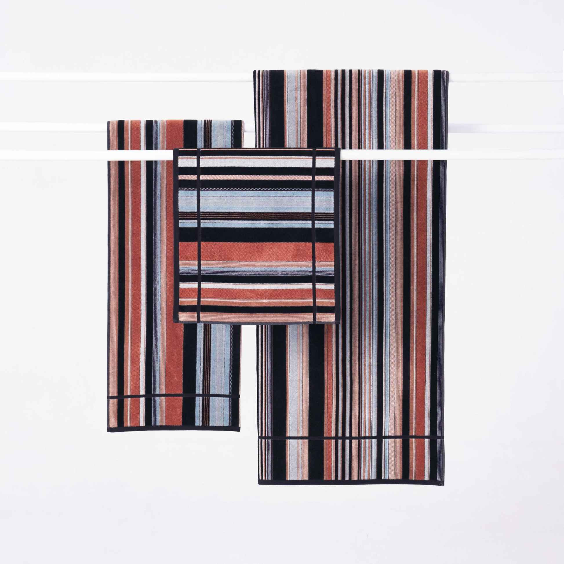 Hung on a clothesline Innate Sunrise Bath sheet and towel with the Innate Ridge Sunrise hand towel 40cm x 70cm, luxury absorbent cotton hand towel inspired by a sunrise landscape, featuring a velour finish on one side and terry cotton on the other, made from 100% OEKO-TEX® certified cotton and responsibly woven in Portugal.