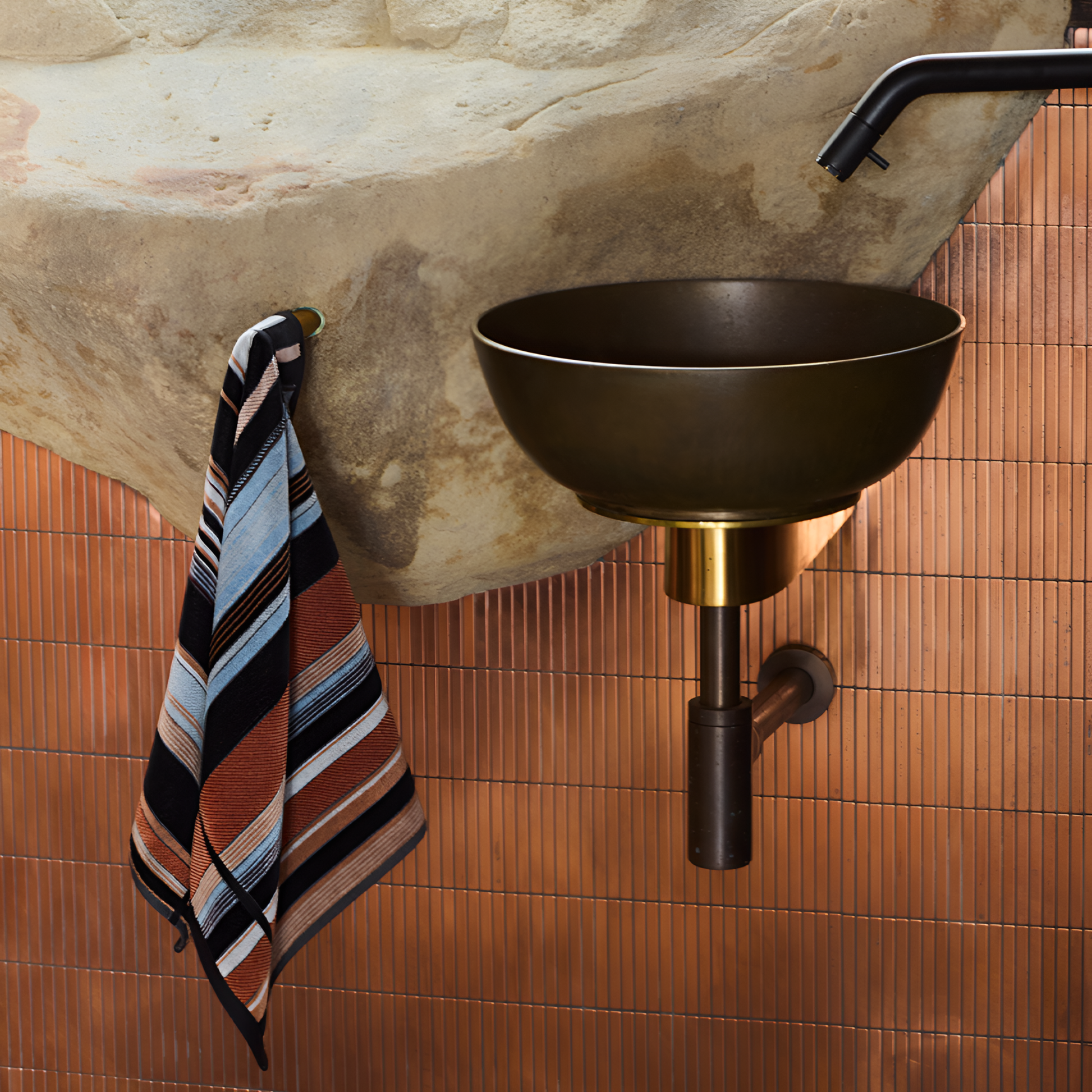 Seen beside a sink, the Innate Ridge Sunrise hand towel 40cm x 70cm, luxury absorbent cotton hand towel inspired by a sunrise landscape, featuring a velour finish on one side and terry cotton on the other, made from 100% OEKO-TEX® certified cotton and responsibly woven in Portugal.