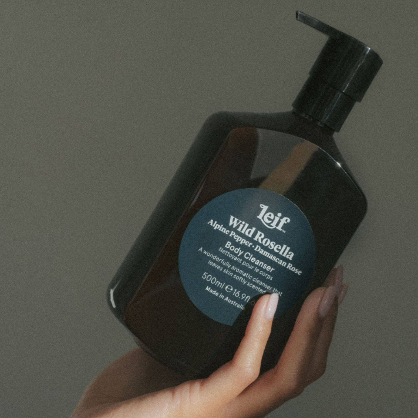 Womans hand holding a bottle of Leif body cleanser Wild Rosella 500ml