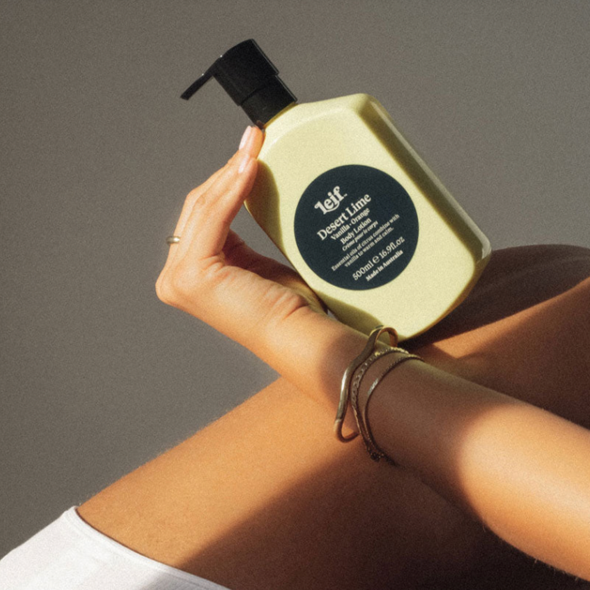 Leif body lotion Desert Lime 500ml balanced on womans back with her hand supporting bottle