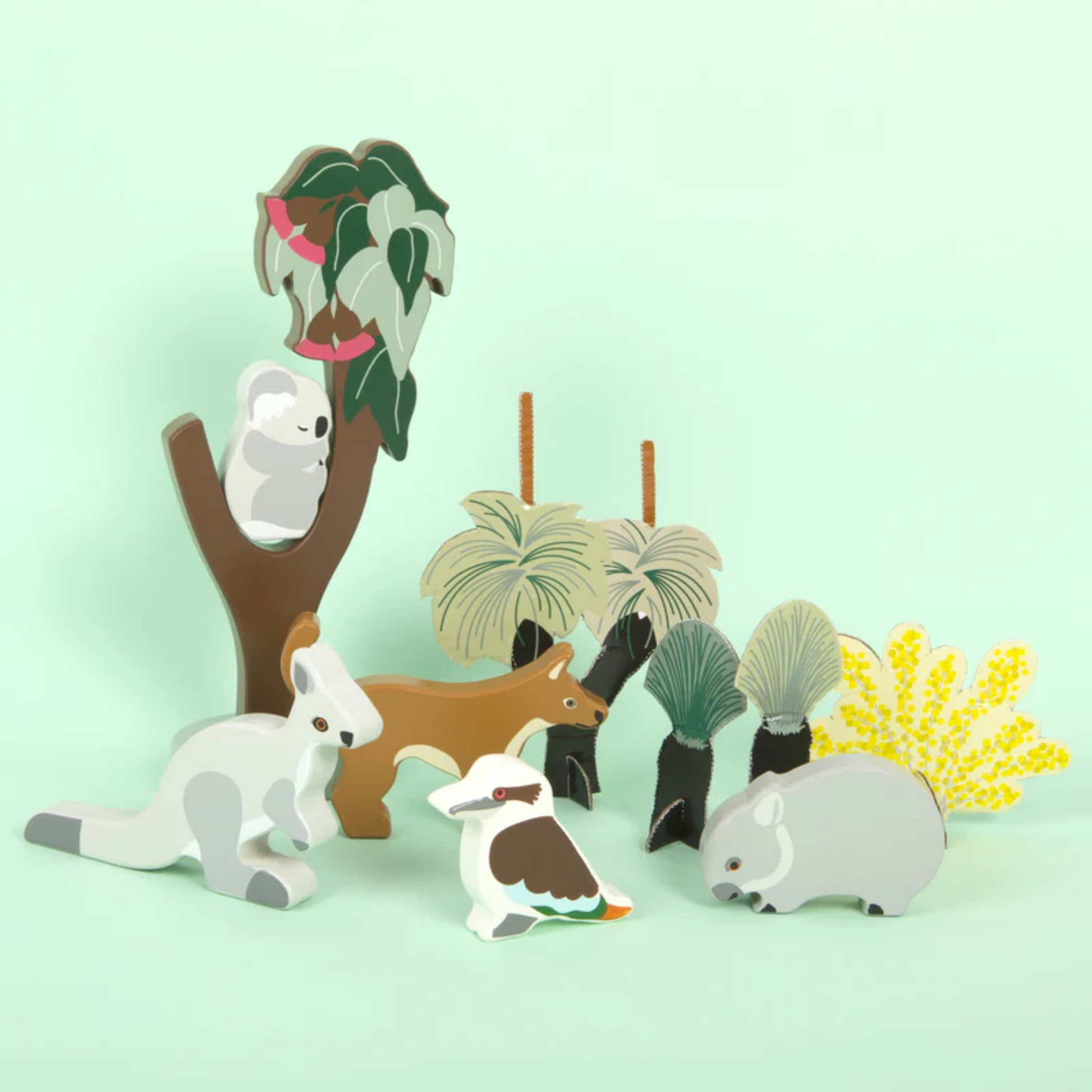 Displayed with a solid bright background Make Me Iconic wooden Australian animal toy set featuring eight native animals and a gum tree, crafted from non-toxic wood with eco packaging - includes kangaroo, koala, wombat, platypus, emu, echidna, dingo, and kookaburra for open-ended play celebrating Aussie wildlife and culture.