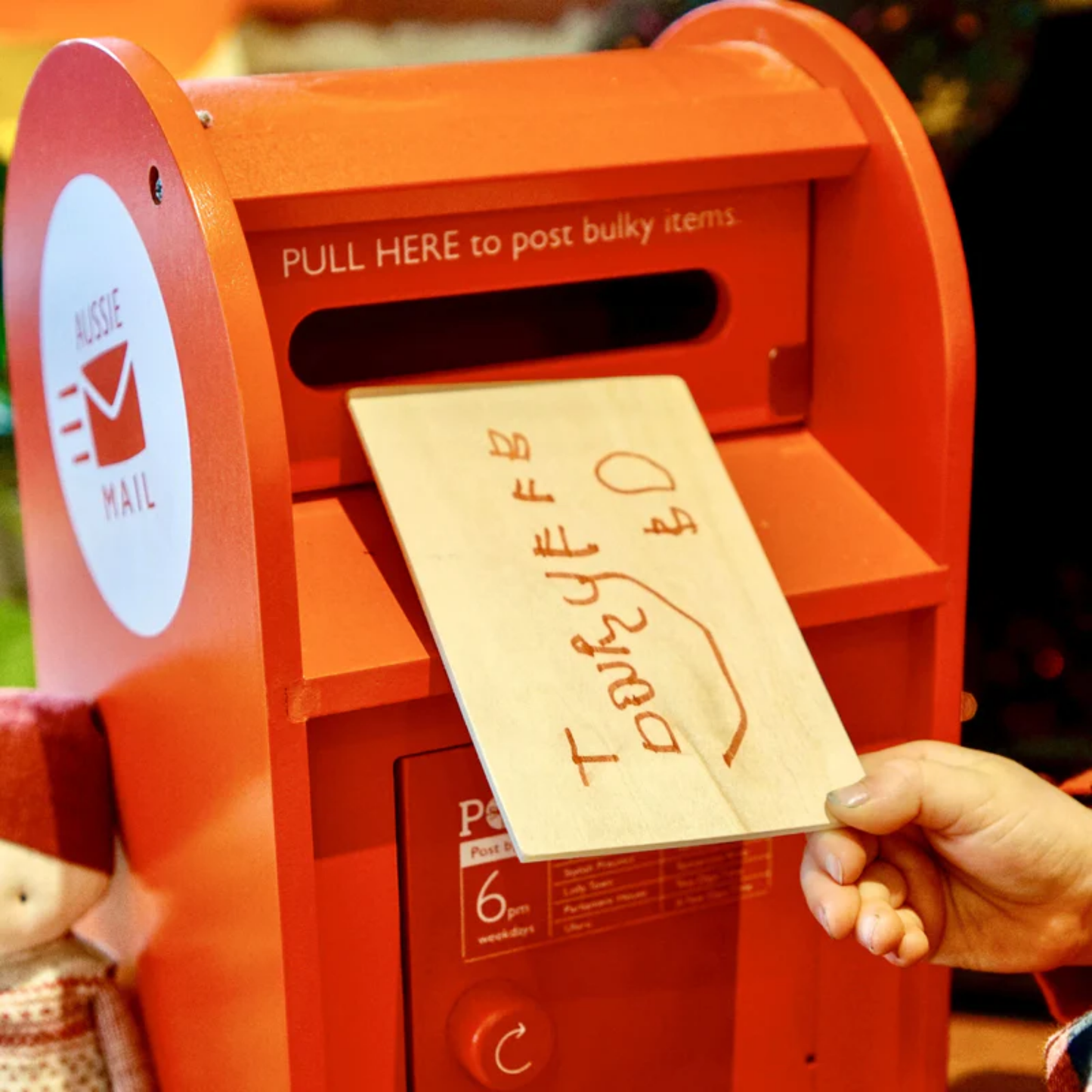 Close up of Make Me Iconic wooden red post box toy set featuring a working pull-down slot, six mix-and-match Velcro stamps, and six wooden letters and postcards - a nostalgic, eco-friendly playset designed in Australia to inspire creativity and role play for children aged 3 and up.