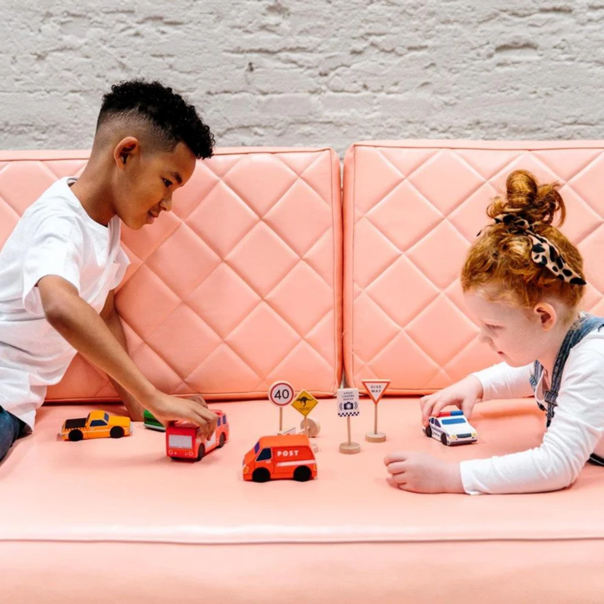 Two kids playing with cars and Make Me Iconic wooden traffic sign play set - multicolor solid wood toy featuring 5 double-sided Australian road signs for imaginative and educational car play.