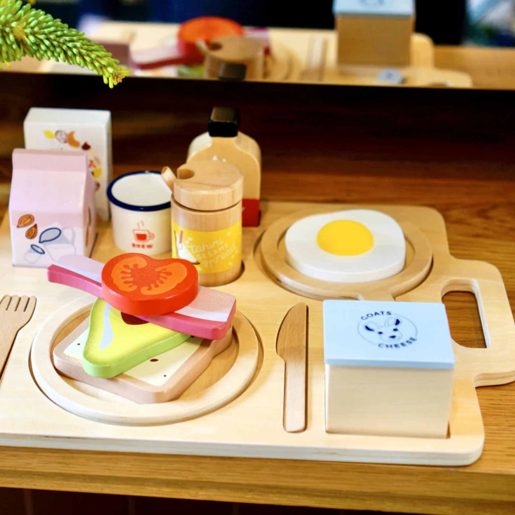 Make Me Iconic wooden toy breakfast set - multicolor wood play set featuring 21 café-style pieces including avocado toast, kombucha, and sliceable goat's cheese for creative pretend play.