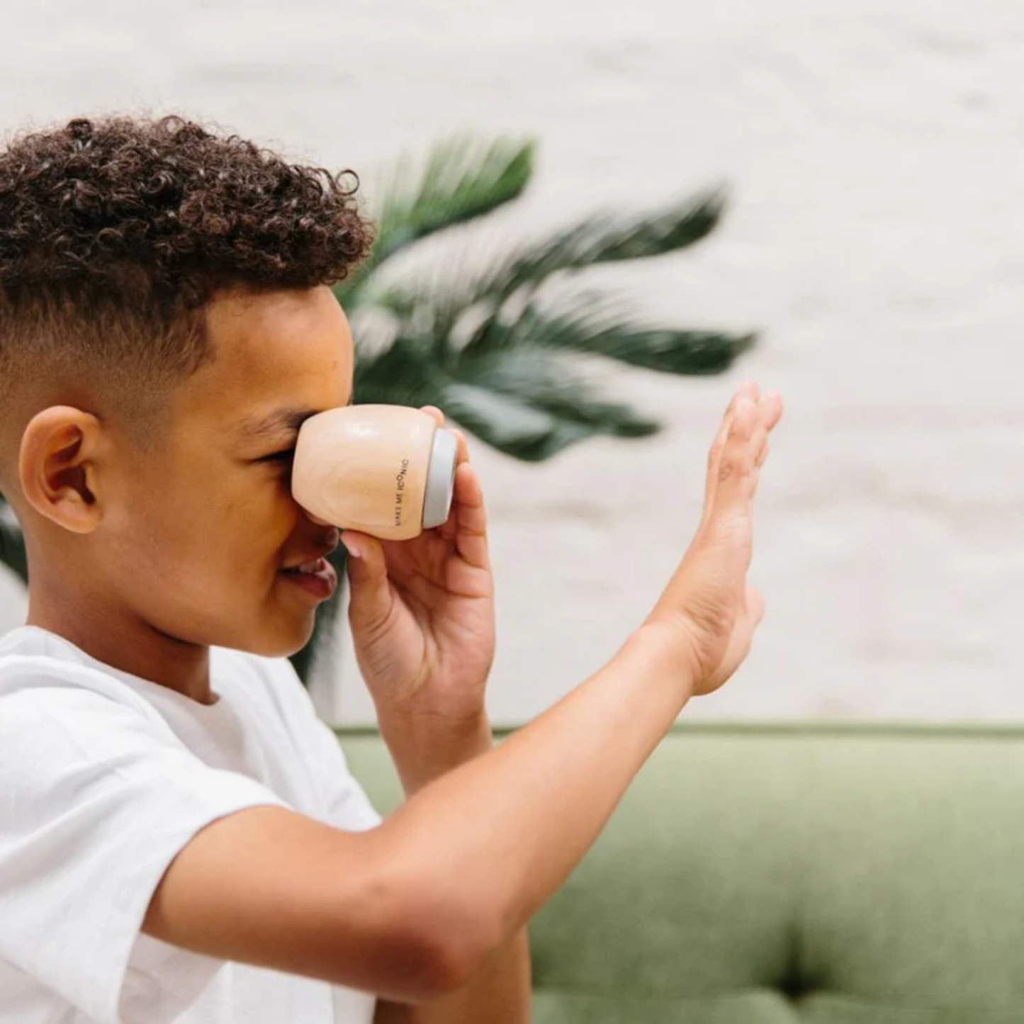 Showing a kid playing the Make Me Iconic wooden kaleidoscope - solid wood kaleidoscope in yellow or soft grey, designed for kids to explore light, color, and patterns through imaginative, screen-free play.