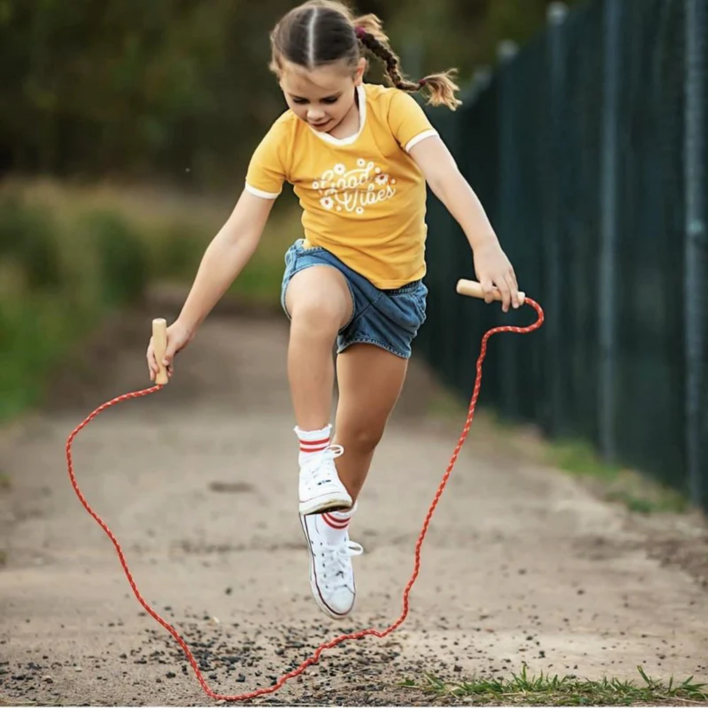 Shown little girl playing Make Me Iconic wooden skipping rope - classic natural wood handles with sturdy neutral rope, designed for kids to build rhythm, balance, and coordination through active, screen-free play