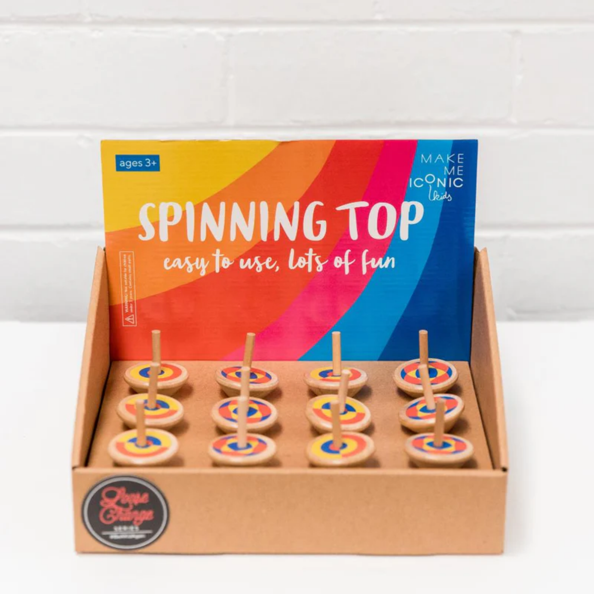 In a tray a group of Make Me Iconic wooden spinning top toy - durable wooden top with colorful painted design, spins smoothly with a flick of the hand for nostalgic, screen-free play.