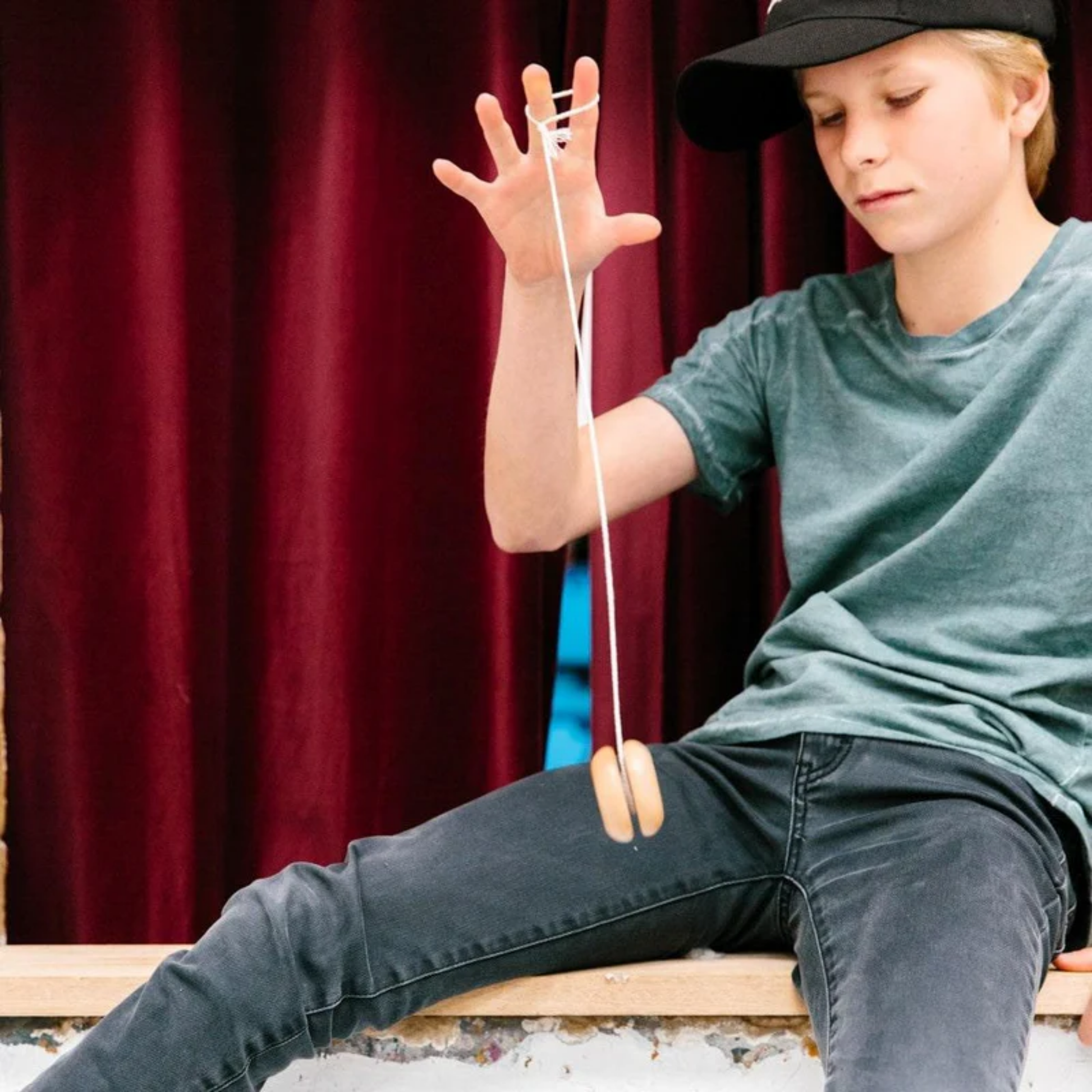 Played by a boy sitting on a window Make Me Iconic wooden yo-yo toy - durable timber yo-yo with retro-style painted designs, crafted for smooth spinning and easy tricks, a nostalgic skill toy for kids and adults.