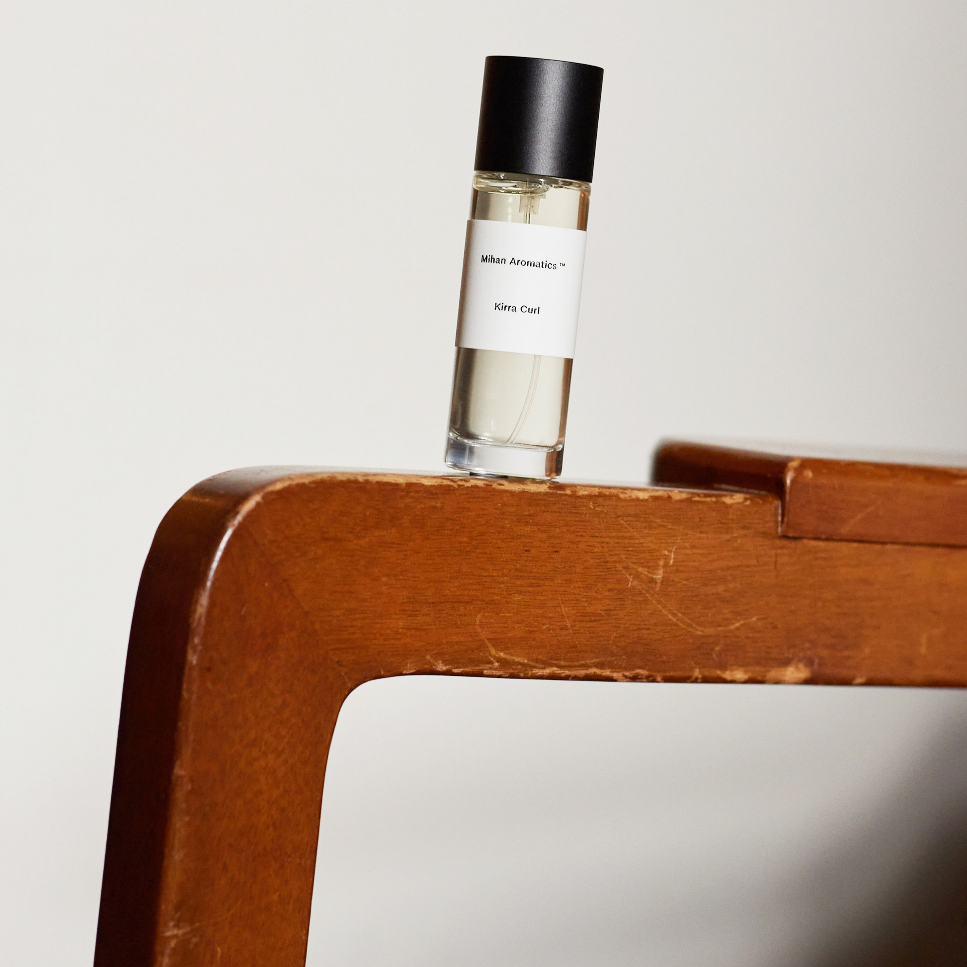 Shown on a wood Mihan Aromatics Kirra Curl Parfum in clear glass bottle, 30ml, woody amber scent blending sea salt, lemon rind, leather, surf wax, and Australian sandalwood. Inspired by sun-soaked surf days along the Australian coast. Hand-filled in Melbourne, cruelty-free and vegan, with 30% perfume concentrate for lasting fragrance.