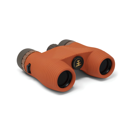 Semi side view of Nocs Provisions Binocular Standard Issue 8X25 Poppy Orange that has multi-coated lenses and premium BaK4 prisms, waterproof, fogproof and compact.