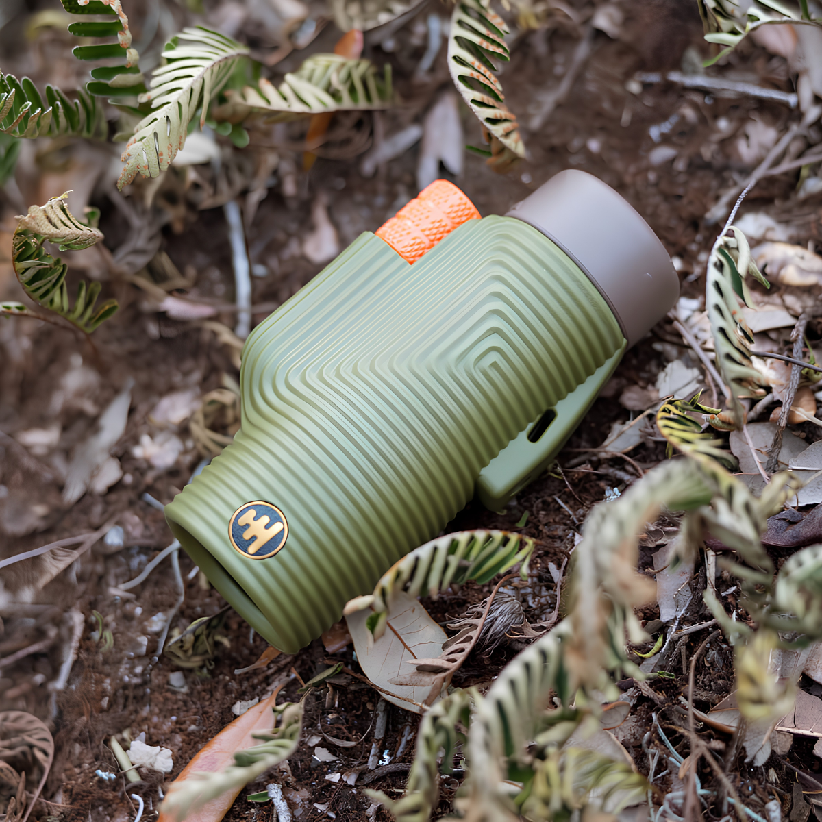 Nocs Provisions Monocular Zoom Tube 8X32 Juniper Green that has fully multi-coated optics, premium BaK4, high quality optical glass, water resistant and compact, shown lying on the forest floor.