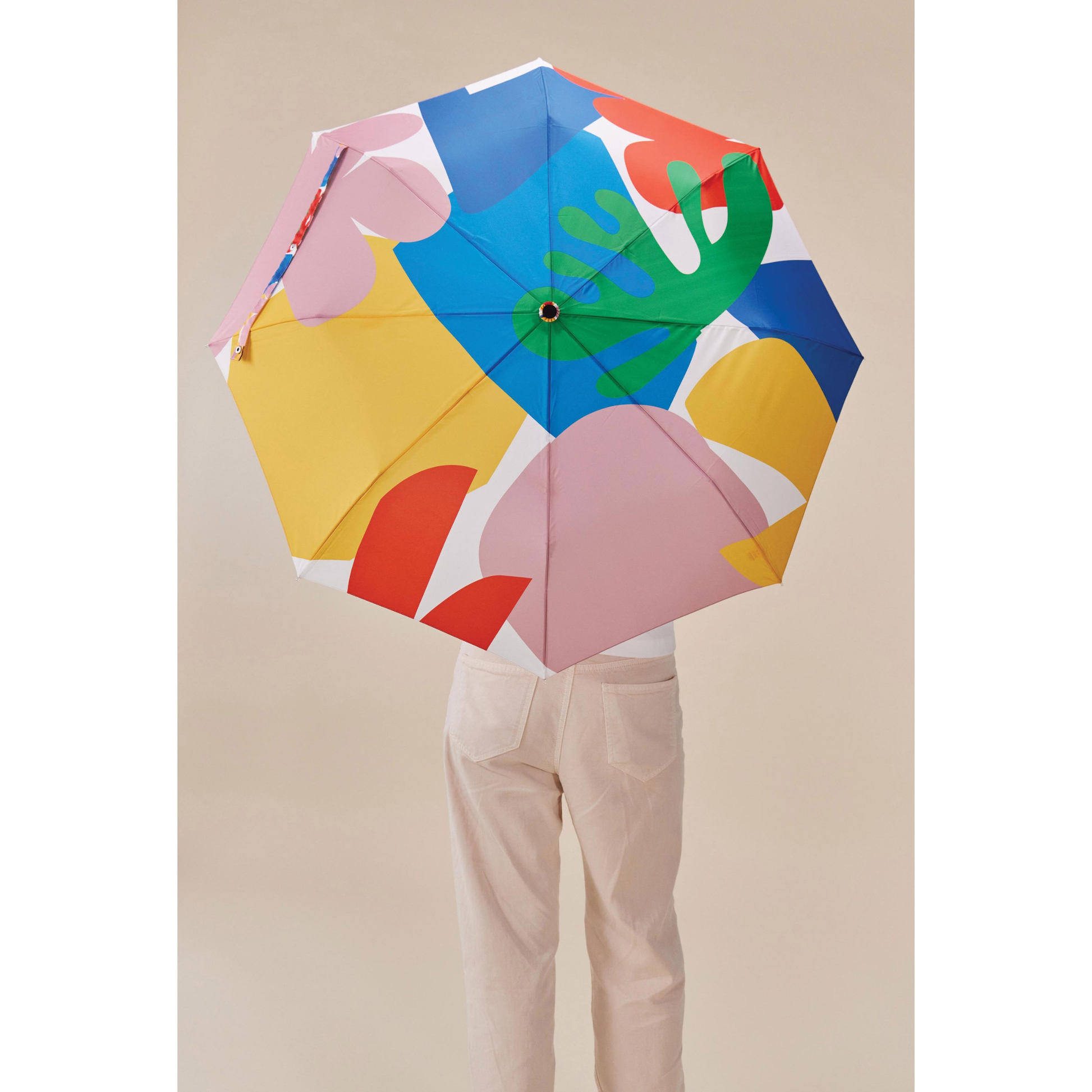 Back view of a person holding the Original Duckhead Duck Umbrella Compact Matisse Print from 100% recycled plastic bottles and robust to keep you dry, it fits into any backpack or tote bag, it is wind resistant, has automatic open button and high-strength steel frame. For everyday use no matter the weather.