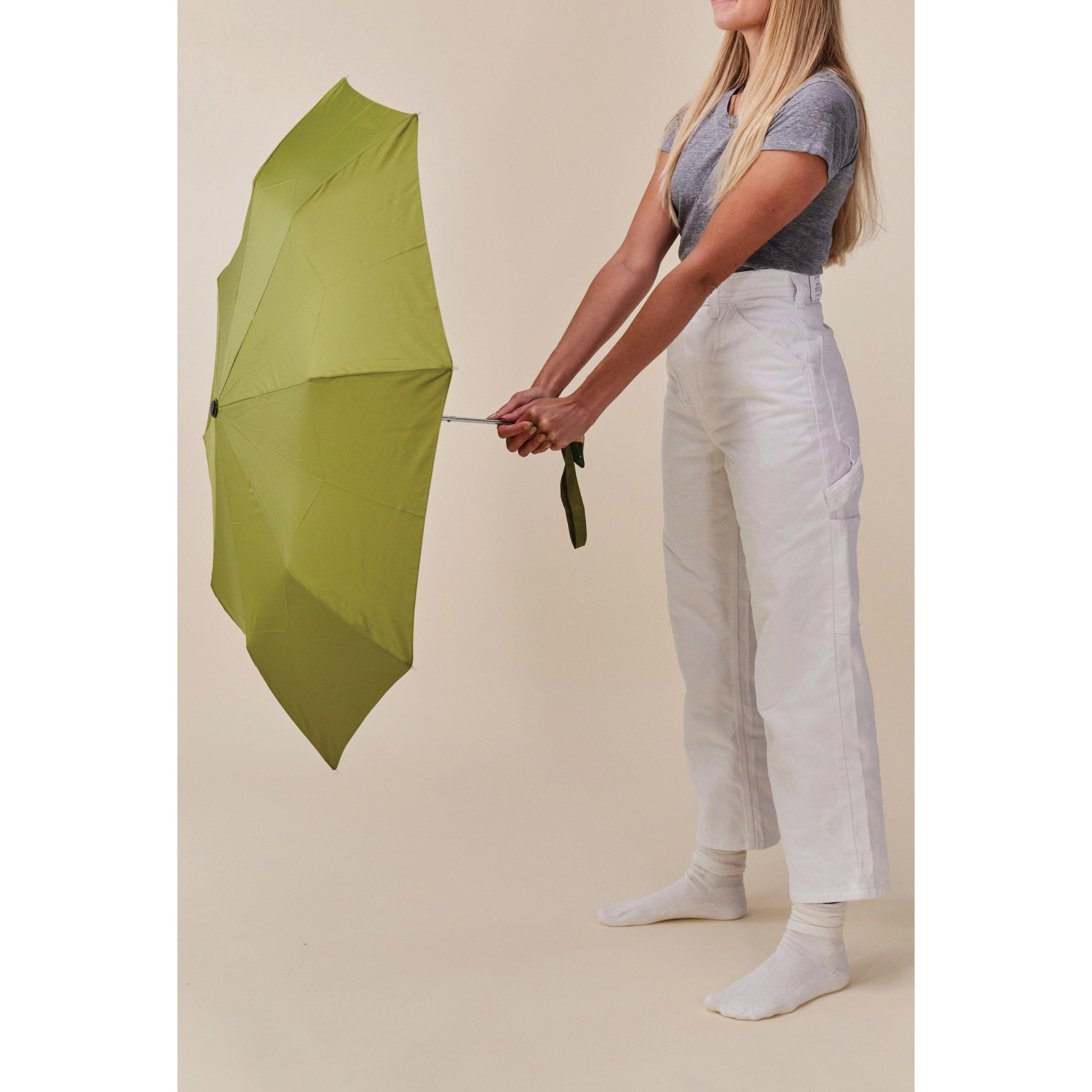 Umbrella held facing forward from Original Duckhead Duck Umbrella Compact Olive from 100% recycled plastic bottles and robust to keep you dry, it fits into any backpack or tote bag, it is wind resistant, has automatic open button and high-strength steel frame. For everyday use no matter the weather.