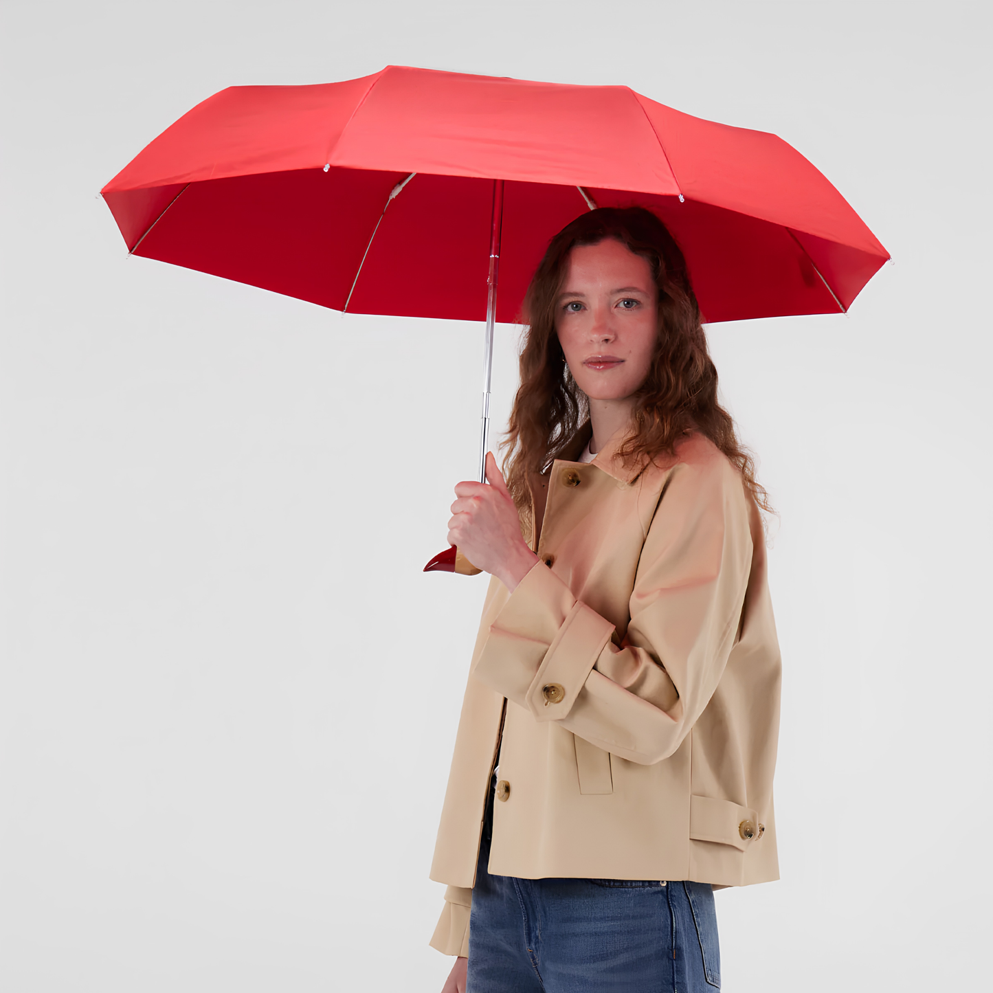 A woman holding the open Original Duckhead Duck Umbrella Compact Red, from sustainable materials.