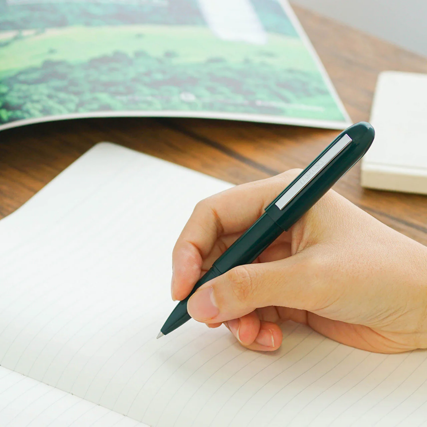 Woman holding Penco small ballpoint pen green writing on paper